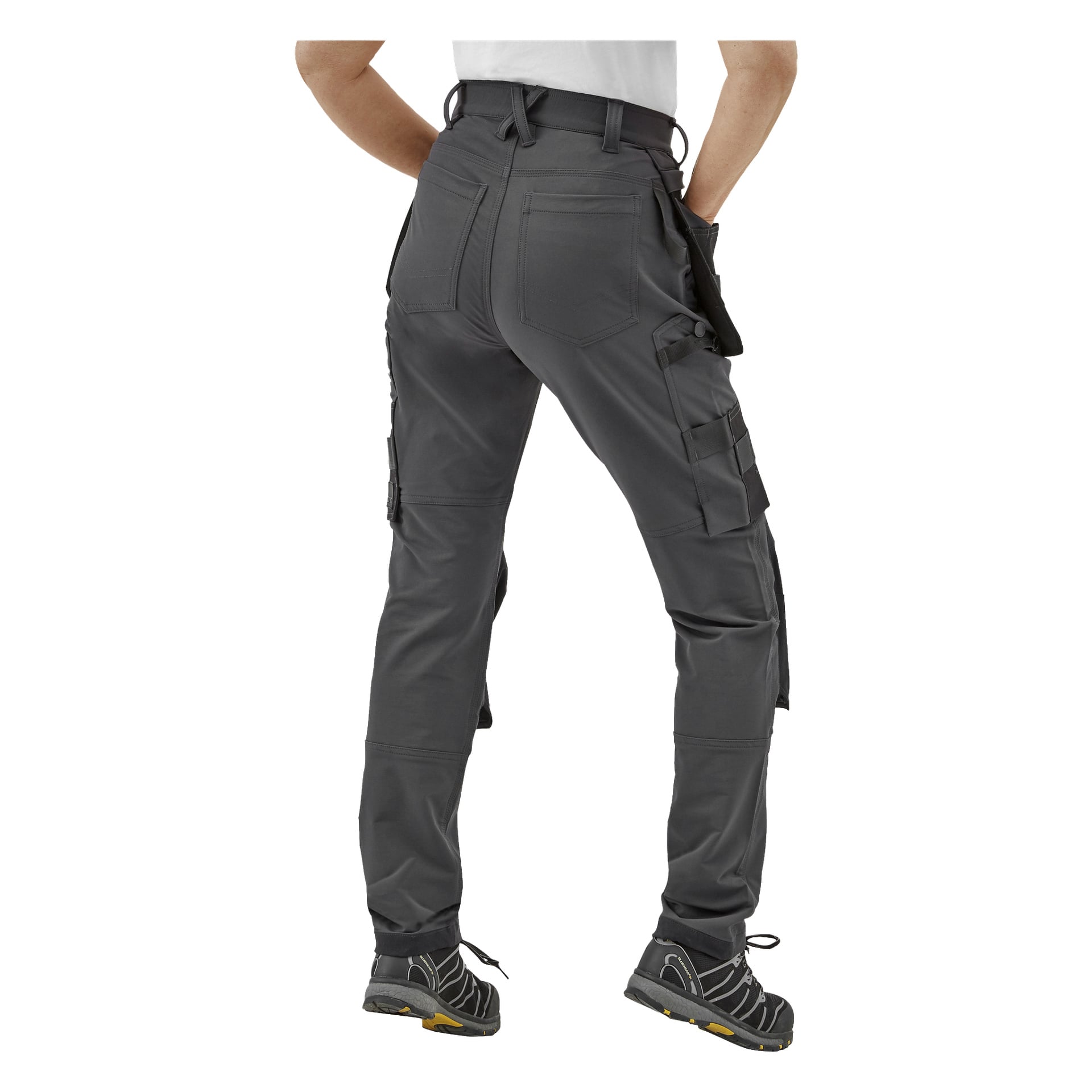 Bluewear Pro Workwear Kvinnors arbetsbyxor Stella i grått, med flera fickor, verktygsöglor och förstärkt söm. Personen visas bakifrån, armarna avslappnade, bär svarta sneakers.