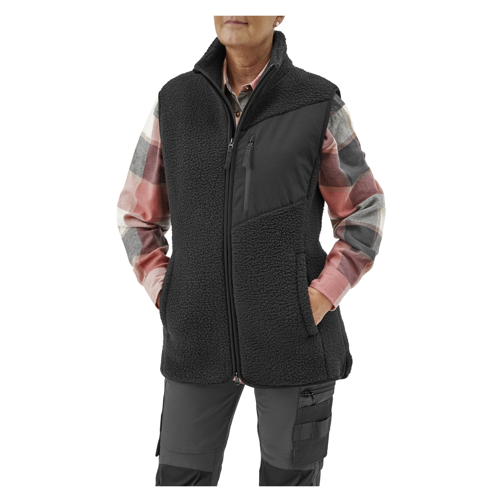 En person visas bära Bluewear Women's pile vest Vivi, en svart fleeceväst med hög krage, dragkedjeförsedda sidofickor och en snedvriden bröstficka, lager på lager över en rutig skjorta i nyanser av rosa, grått och vitt. Deras händer placeras i västens sidofickor.