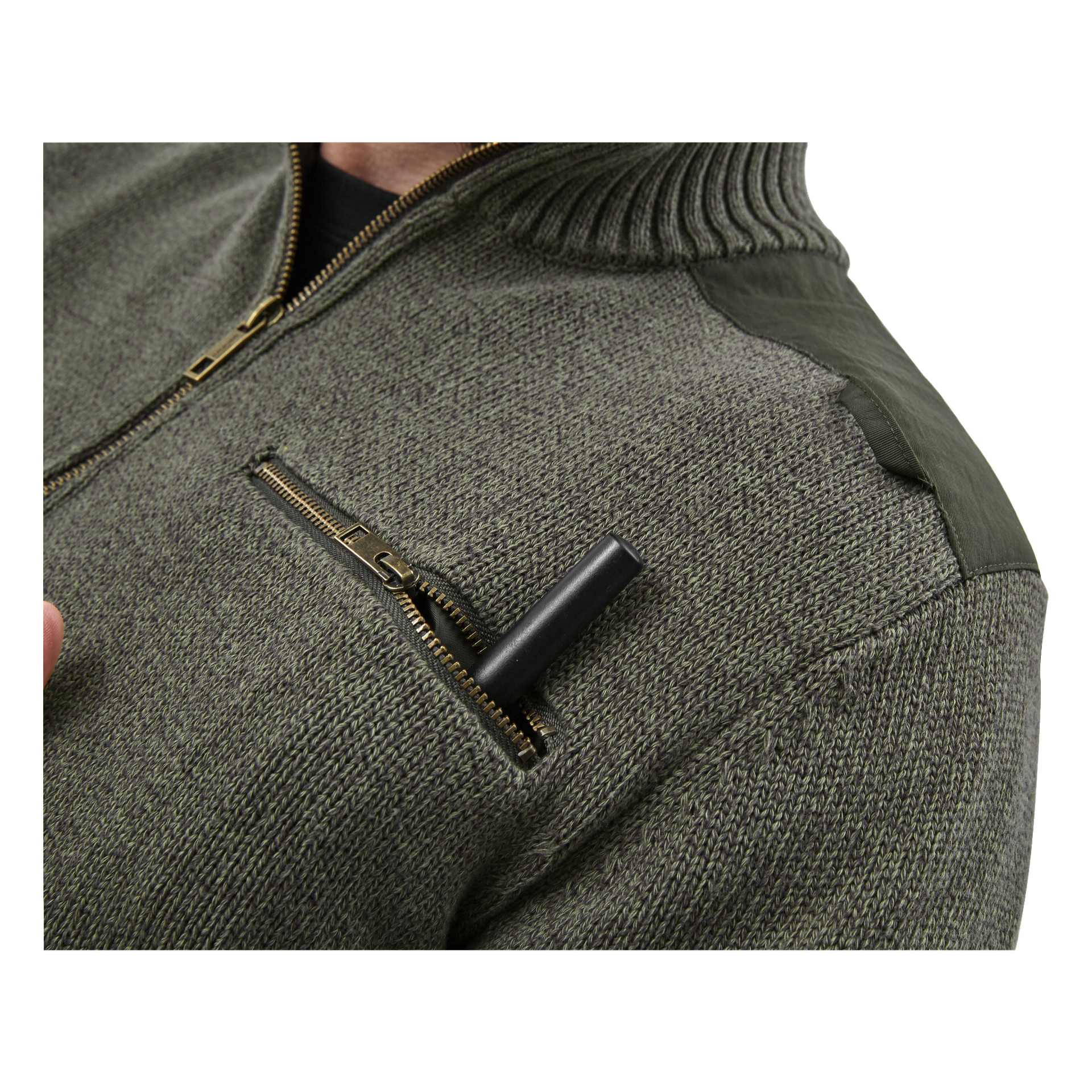 En närbild visar någon klädd i den gröna Kayoba Outdoor Knitted Cannock herrjakttröjan, med en svart penna eller penna delvis instoppad i den dragkedjeförsedda bröstfickan.