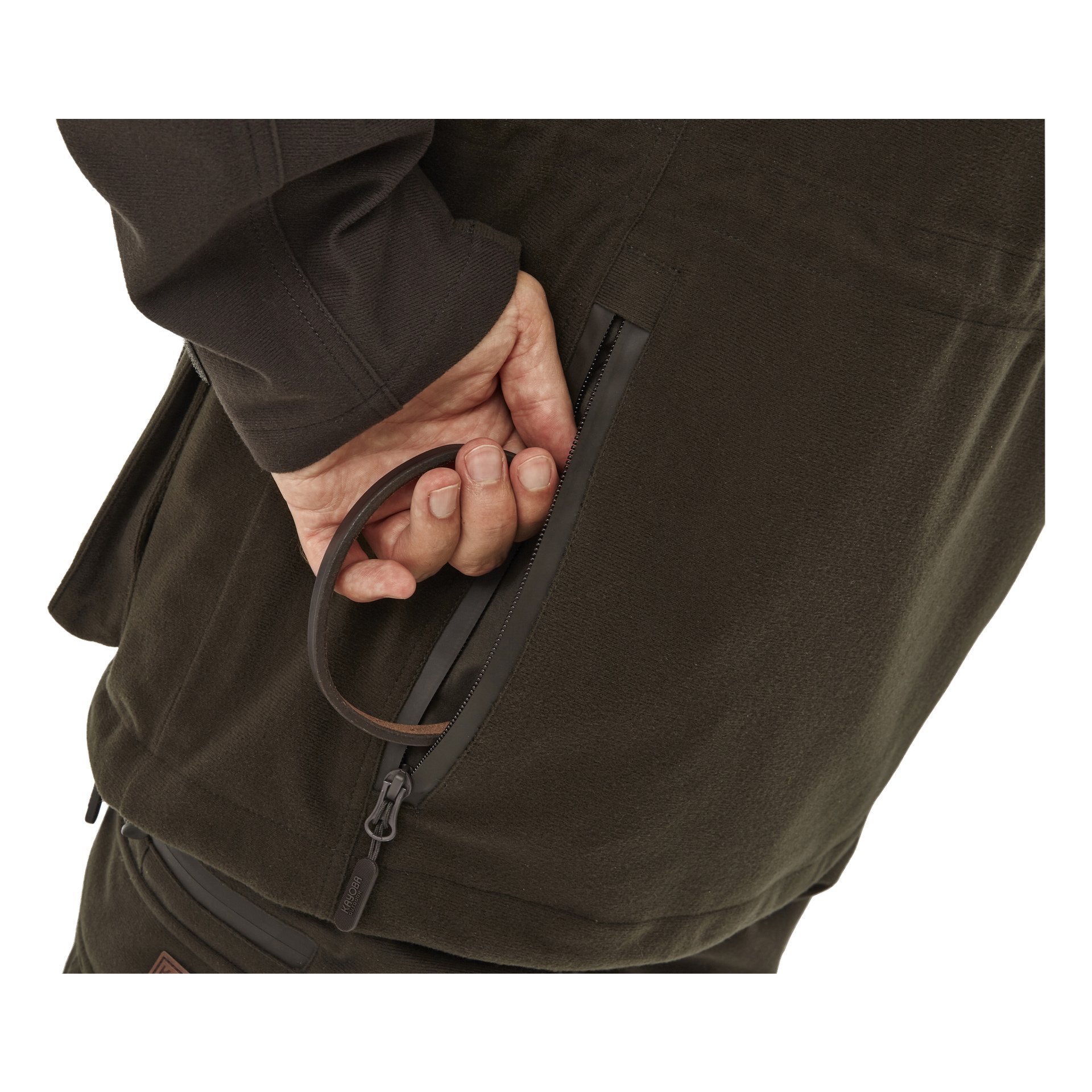Klädd i mörka kläder greppar en person en brun ögla som är kopplad till dragkedjan på en Kayoba Outdoor Cannock Superior jaktjacka och drar den delvis upp. Fokus ligger på deras hand, dragkedjan och motsvarande del av jackan.