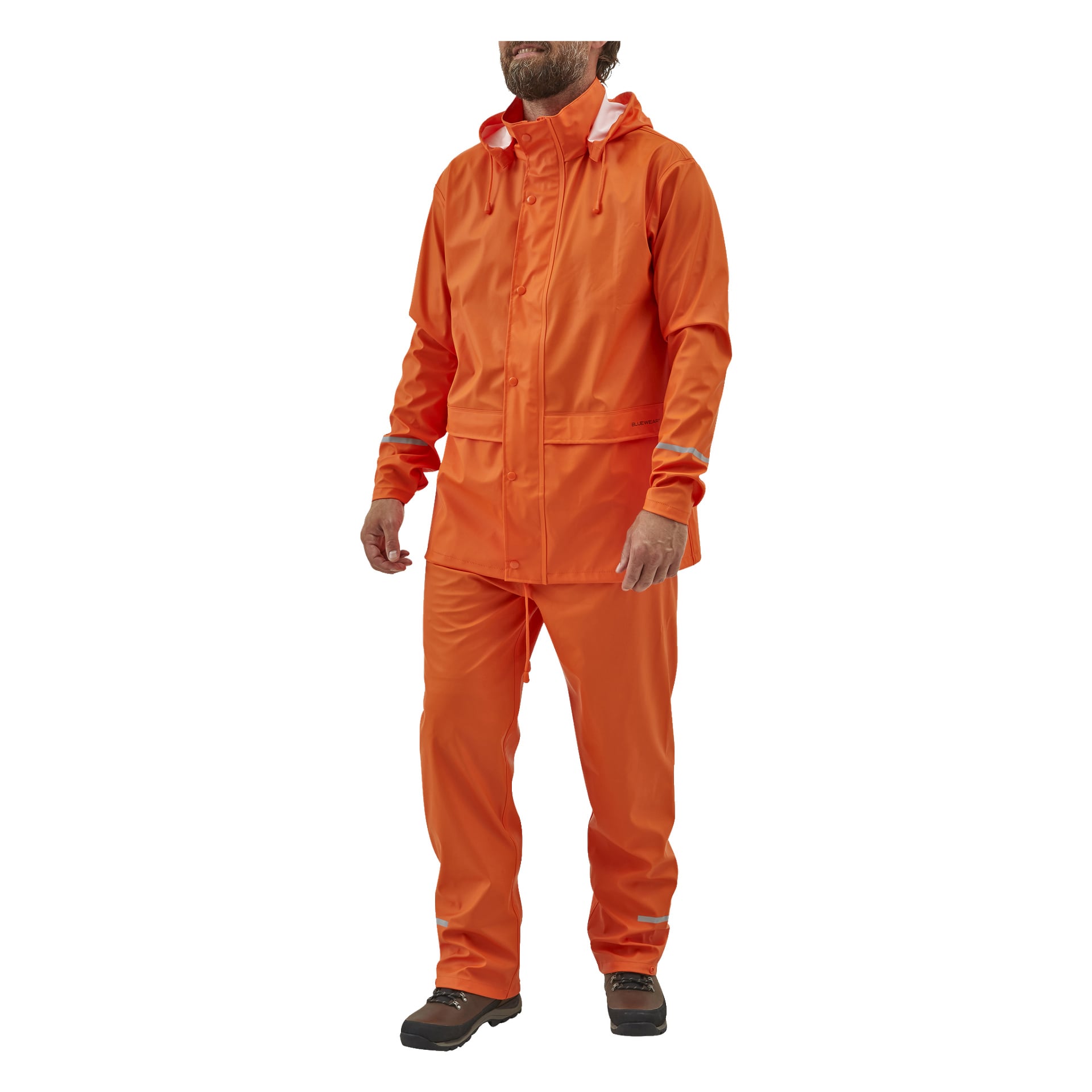 Noen står litt vendt til siden, kledd i Bluewear Rainsuit—en livlig oransje vanntett jakke og matchende bukser med hette og reflekterende striper. De har på seg svarte sko kantet med brune kanter.