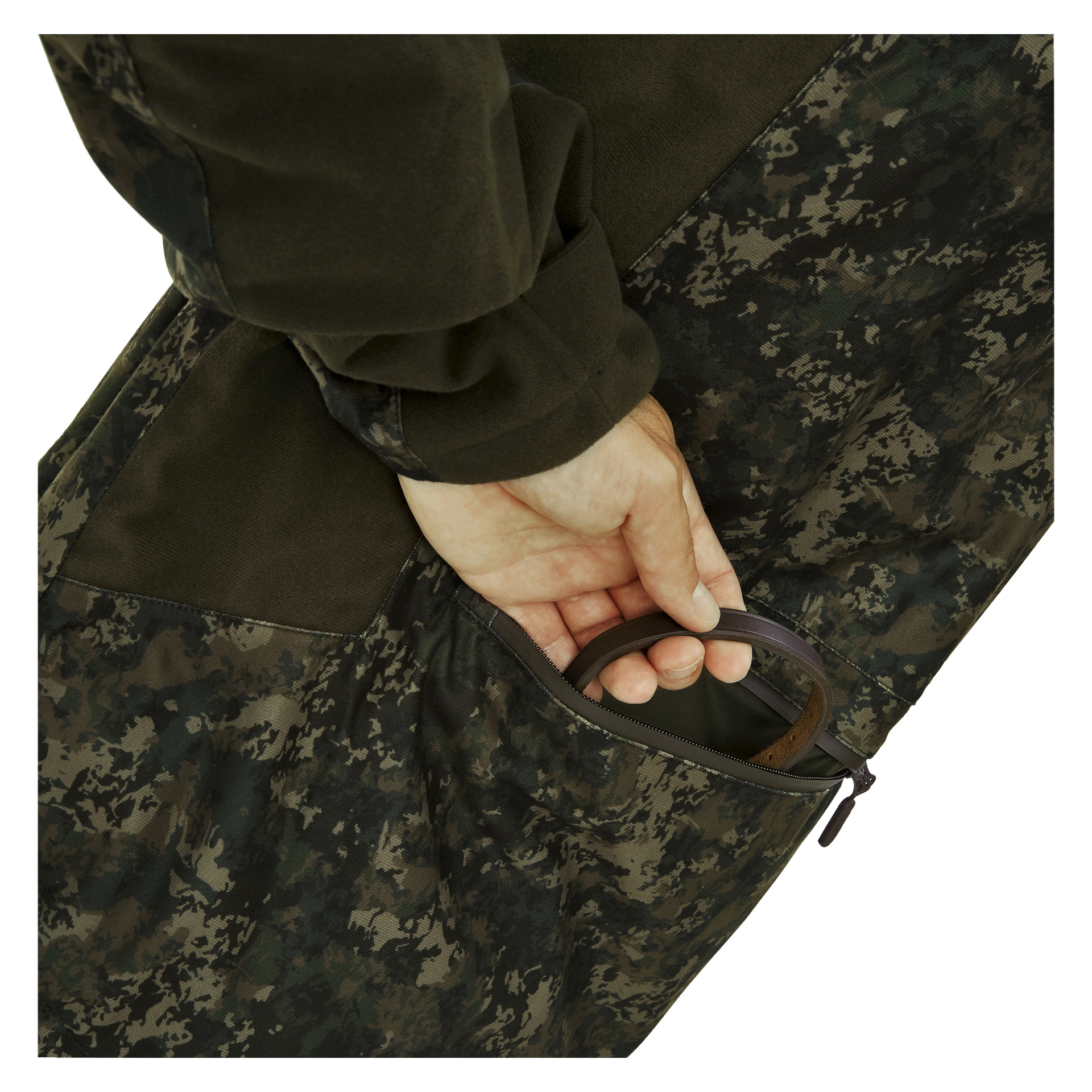 En person klädd i Kayoba Outdoor Men's jaktjacka Cannock Camo stoppar handen i en dragkedjasförsedd sidoficka och håller en brun läderrem inuti.