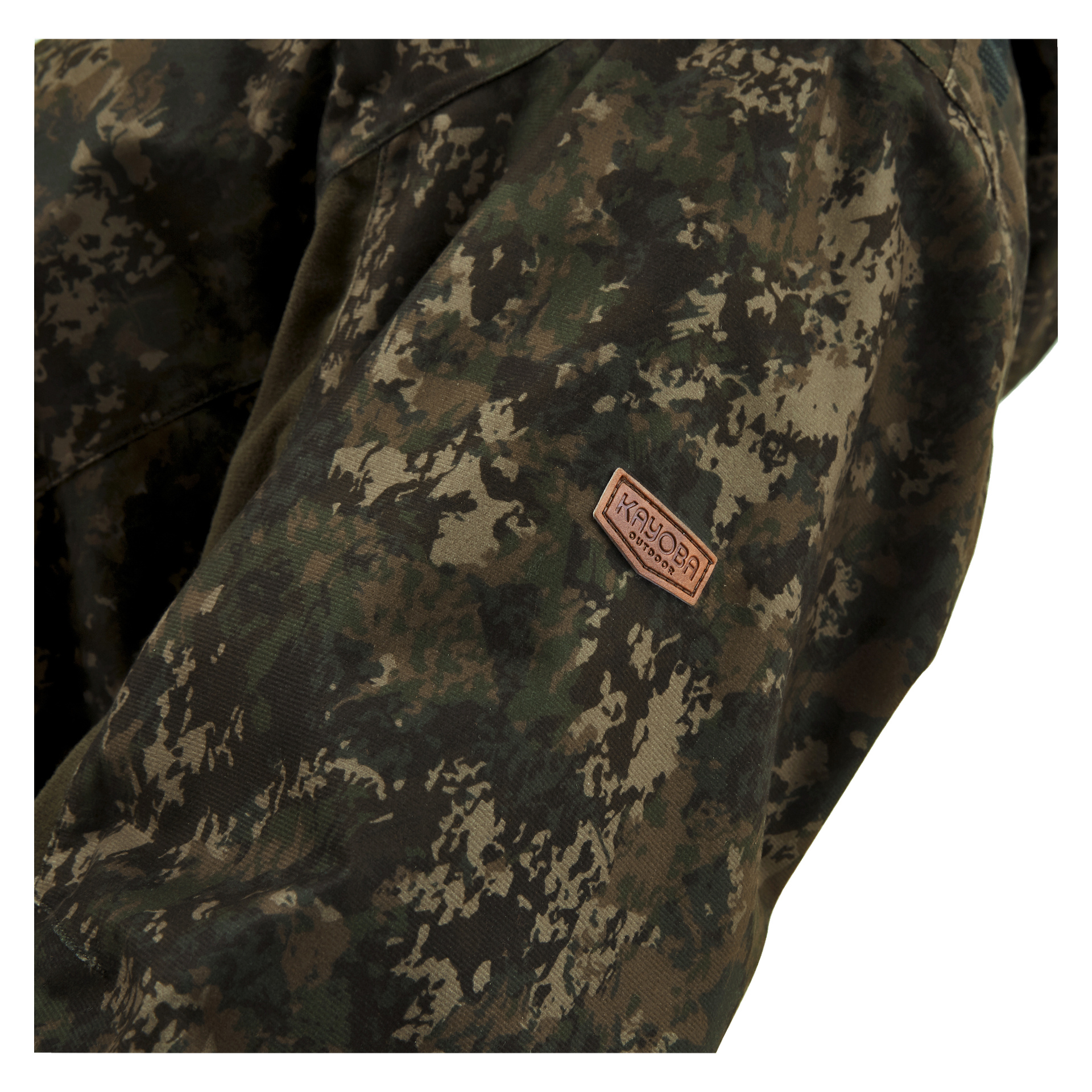 Närbild på Cannock Camo herrjaktjacka av Kayoba Outdoor, som visar dess kamouflagetyg och en liten ljusbrun rektangulär lapp med mörkare text där det står "GROVA OCH ROBUSTA KLÄDER" sydd på.
