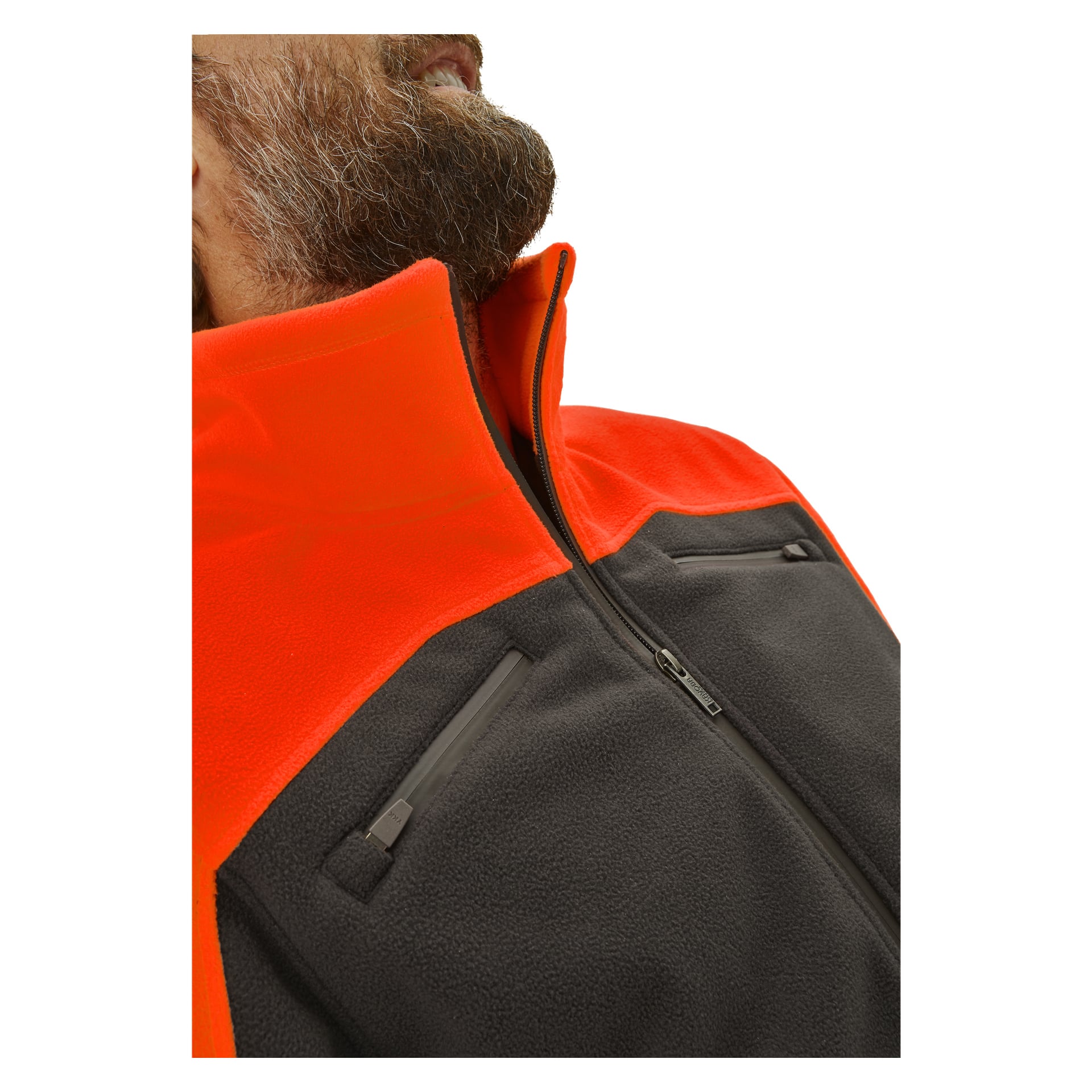 En närbild på en person klädd i Kayoba Outdoor herrjacka Grimsö fleecejacka, med orange överdel och mörkgrå underkropp med två dragkedjefickor på bröstet. Individens skägg och en del av ansiktet är synliga.