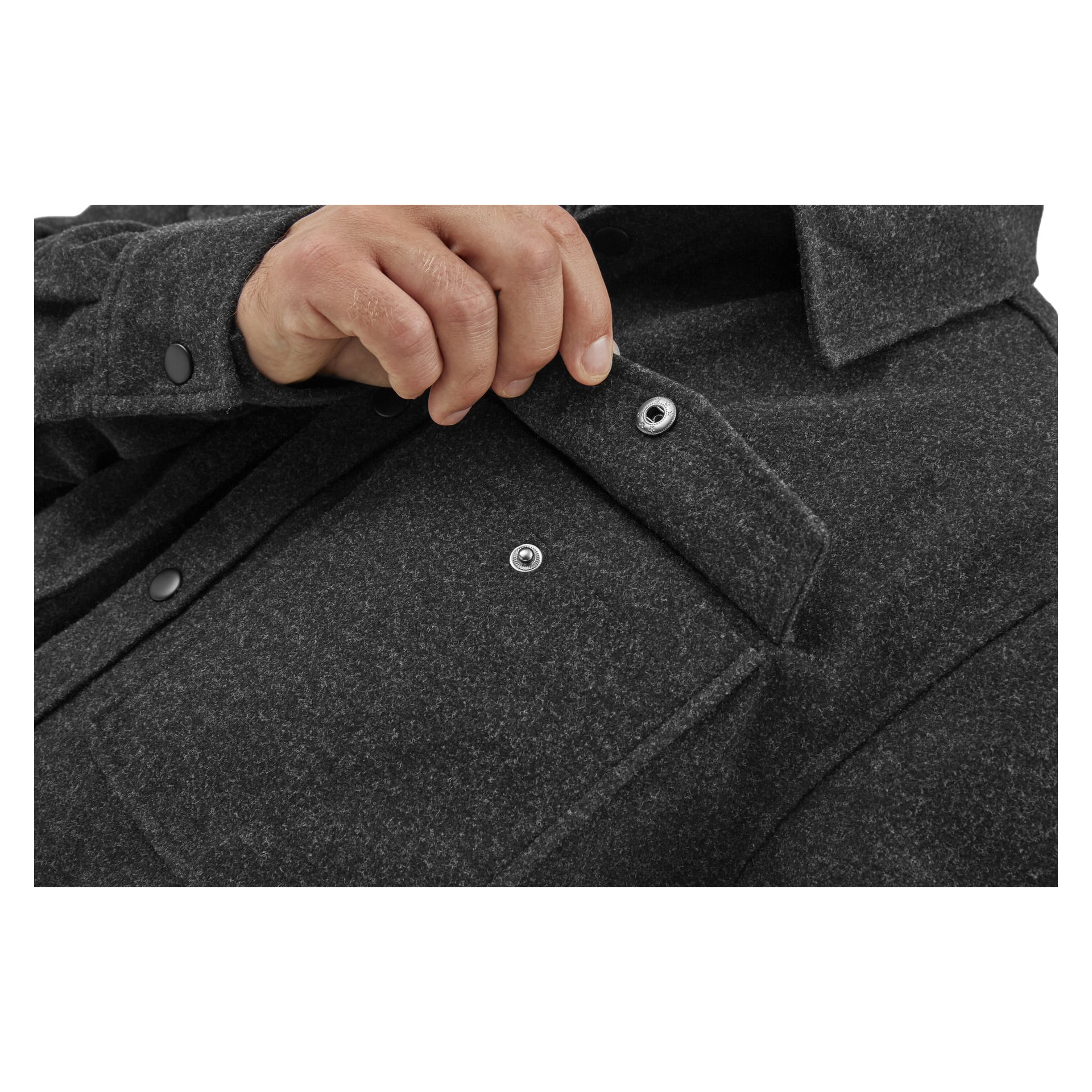 Käsi pitää kiinni tummanharmaan Kayoba Outdoorin Overshirt Men Idhult -paidan yläosasta, korostaen sen nappeja ja taskua.