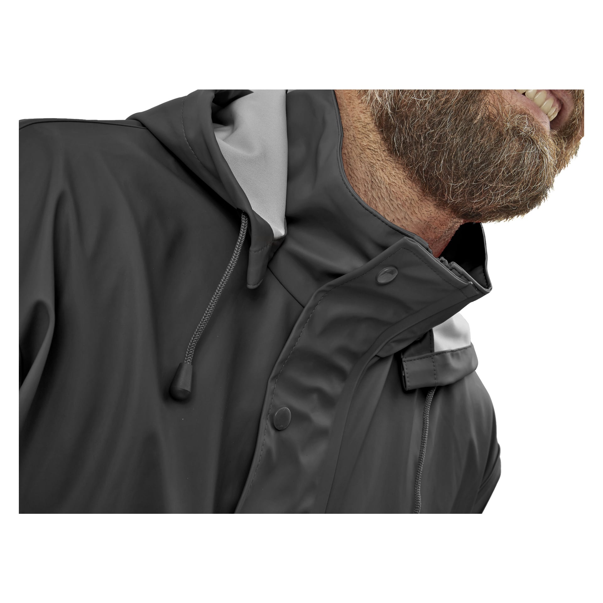 En skjeggete mann vises i nærbilde, med et subtilt smil iført Bluewear Rainsuit—en mørk, hettejakke med lys grå kant. Bare munnen, skjegget og deler av jakken kan sees.