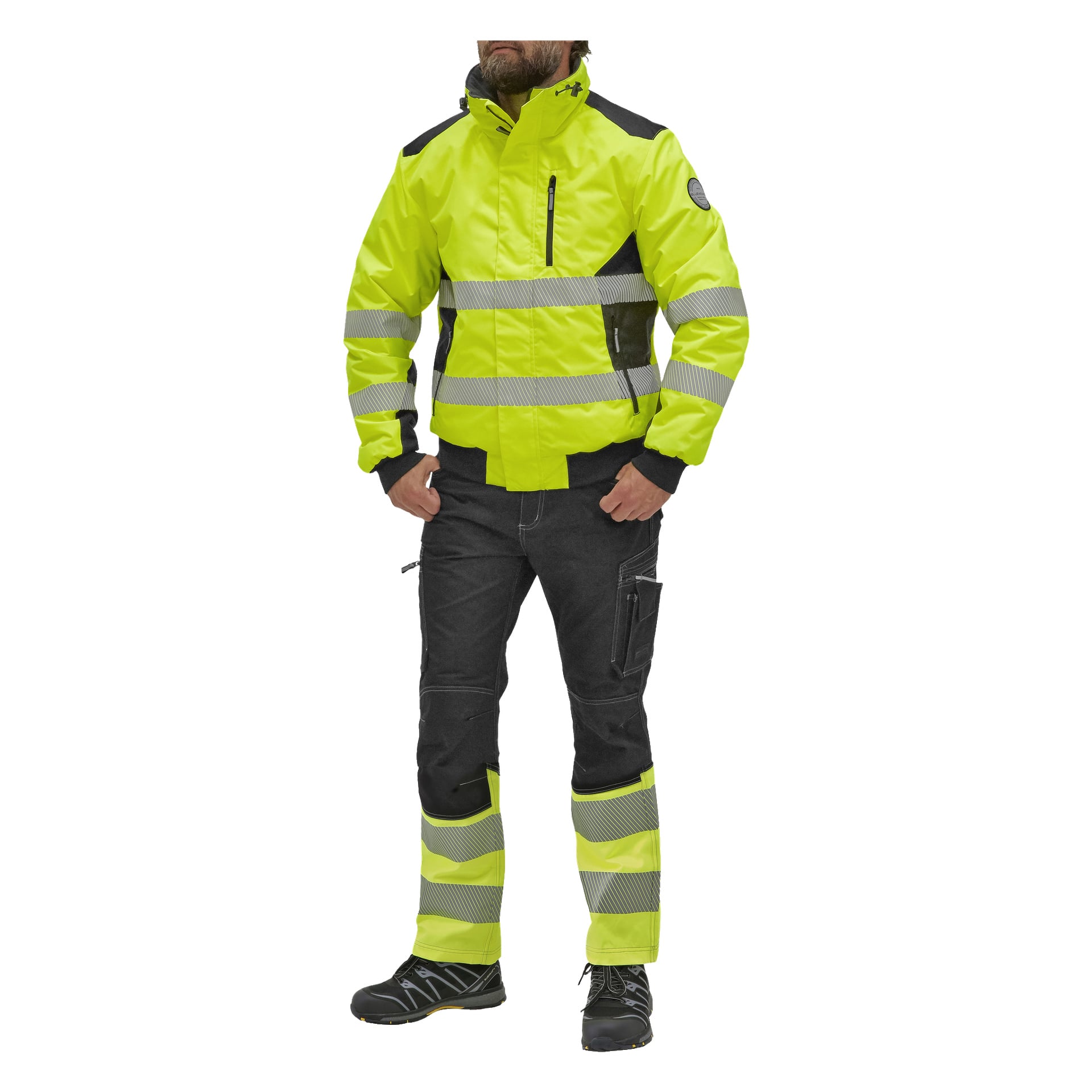 En person klädd i en gul och svart Bluewear Warm-fodrad Hi-Vis Hamilton-jacka med reflekterande ränder, matchande byxor, svarta handskar och svarta arbetsskor.