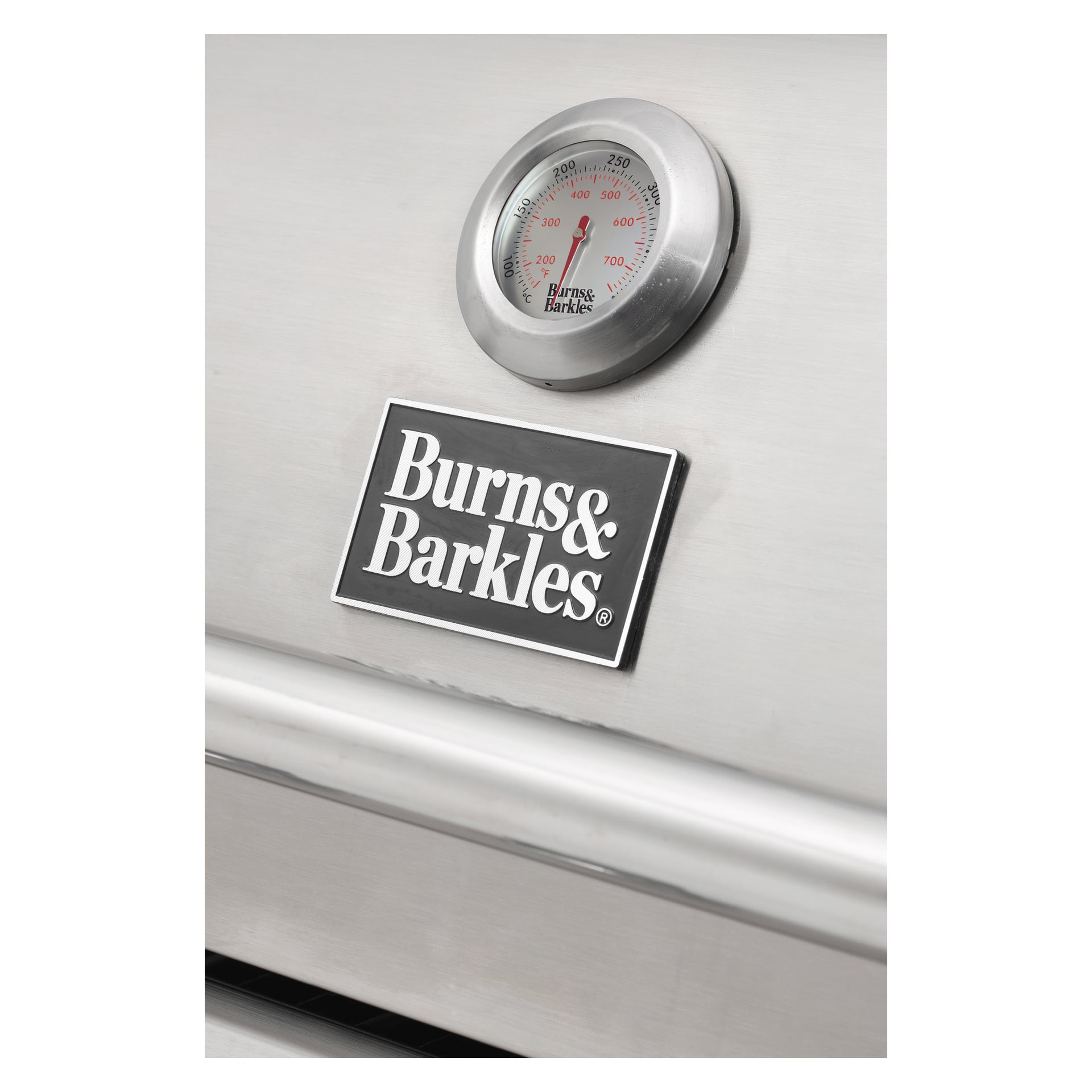 Närbild av Burns & Barkles Steely King 5042B gasgrill med en slank rostfri stålfasad, en framträdande rund temperaturmätare och märkets namnskylt på framsidan.