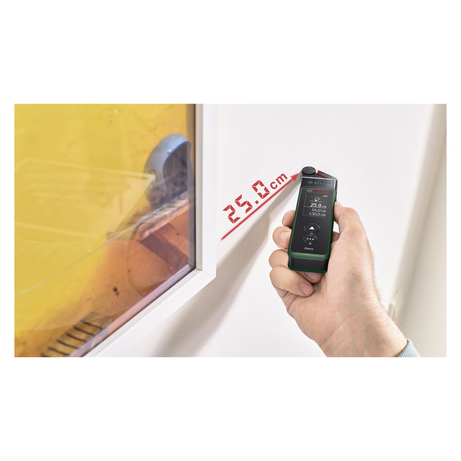 En hand håller Bosch-hjuladaptern för Zamo IV nära ett fönster med gulaktig ton, och dess digitala display visar en mätning på 25,0 cm i rött.