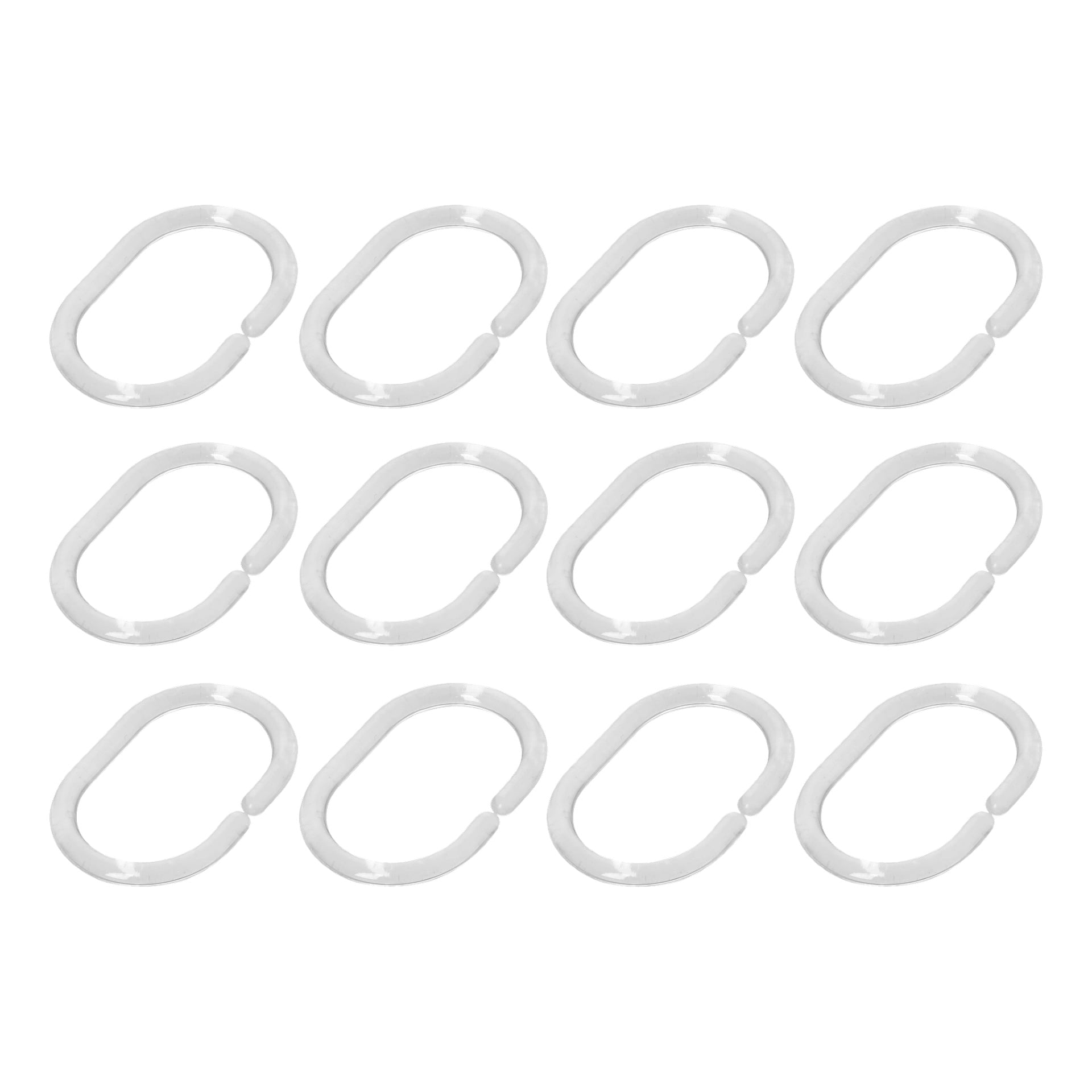 Tolv silverfärgade, ovala EKVIP-gardinringar är prydligt uppställda i fyra rader. Varje ring i uppsättningen av 12 har en liten öppning på ena sidan.