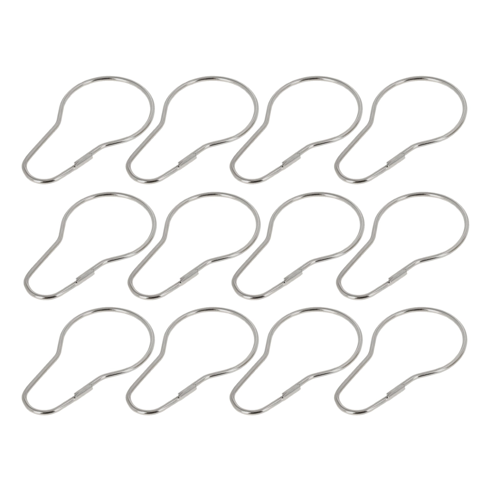 Tolv silver-, metall- och tårdroppsformade gardinringar från EKVIP är arrangerade i prydliga rader. Ringarna är jämnt fördelade och ser helt nya ut.