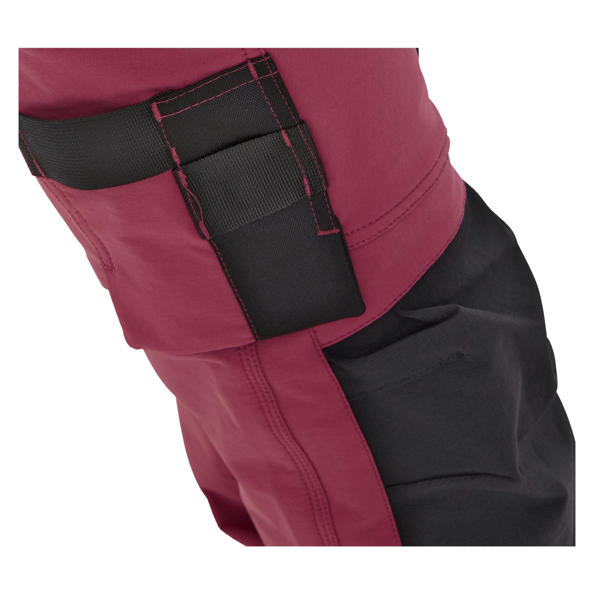 Närbild på någon som bär Bluewear Pro Workwear Women's Stella i rött och svart, med förstärkt söm och en delvis öppen svart sidoficka som framhäver det starka tyget och den kvalitativa byggnaden.