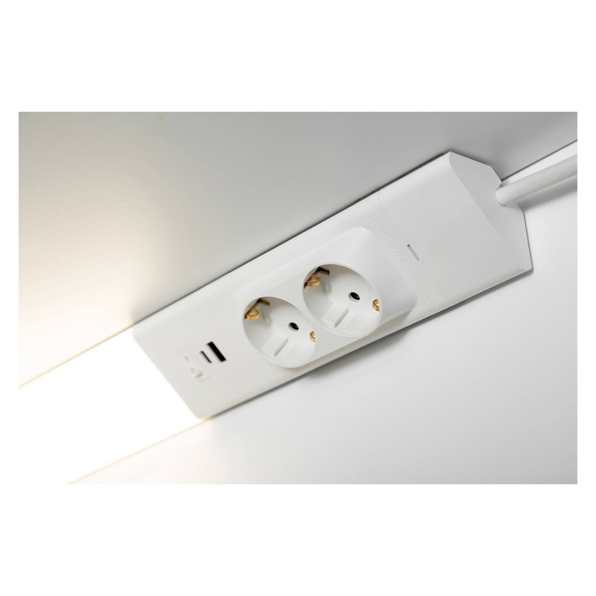 En vit, väggmonterad Anslut Worktop LED-lampa är placerad nära ett takhörn. Den inkluderar två europeiska eluttag och två USB-laddningsportar, med viss synlig ledning.