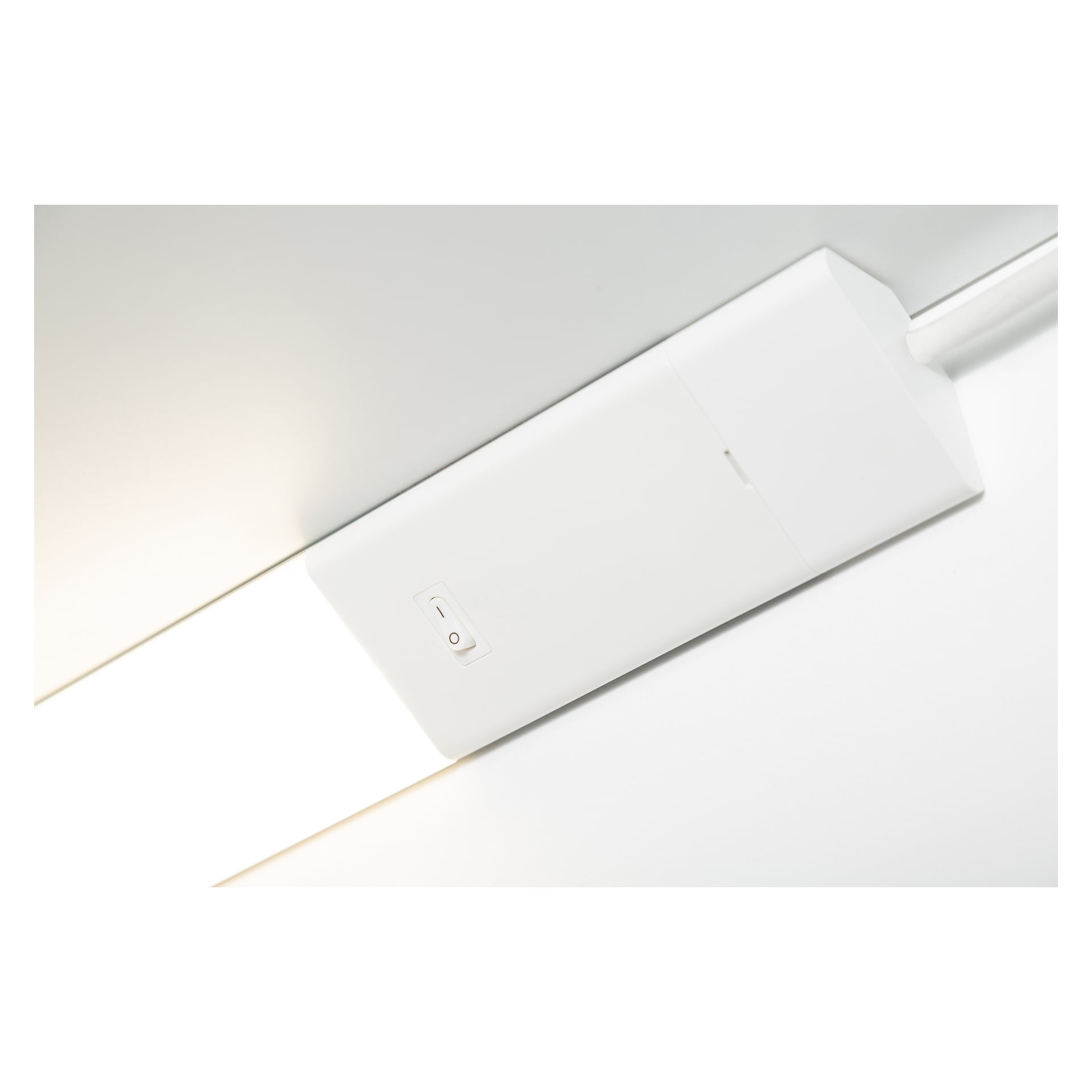En närbild av en Anslut Worktop LED-lampa visar dess rektangulära form monterad i taket, med en liten strömbrytare på locket och en vit elkabel som går in från höger sida.