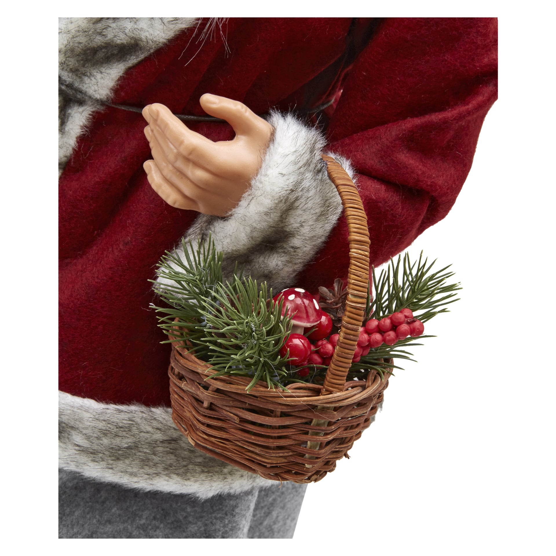 Zbliżenie na rękę trzymającą kosz "Mrs. Claus" EKVIP, w którym znajdują się sztuczne gałęzie sosny, czerwone jagody i grzyby. Osobnik ubrany jest w czerwono-szary płaszcz z futrzanym obszyciem.
