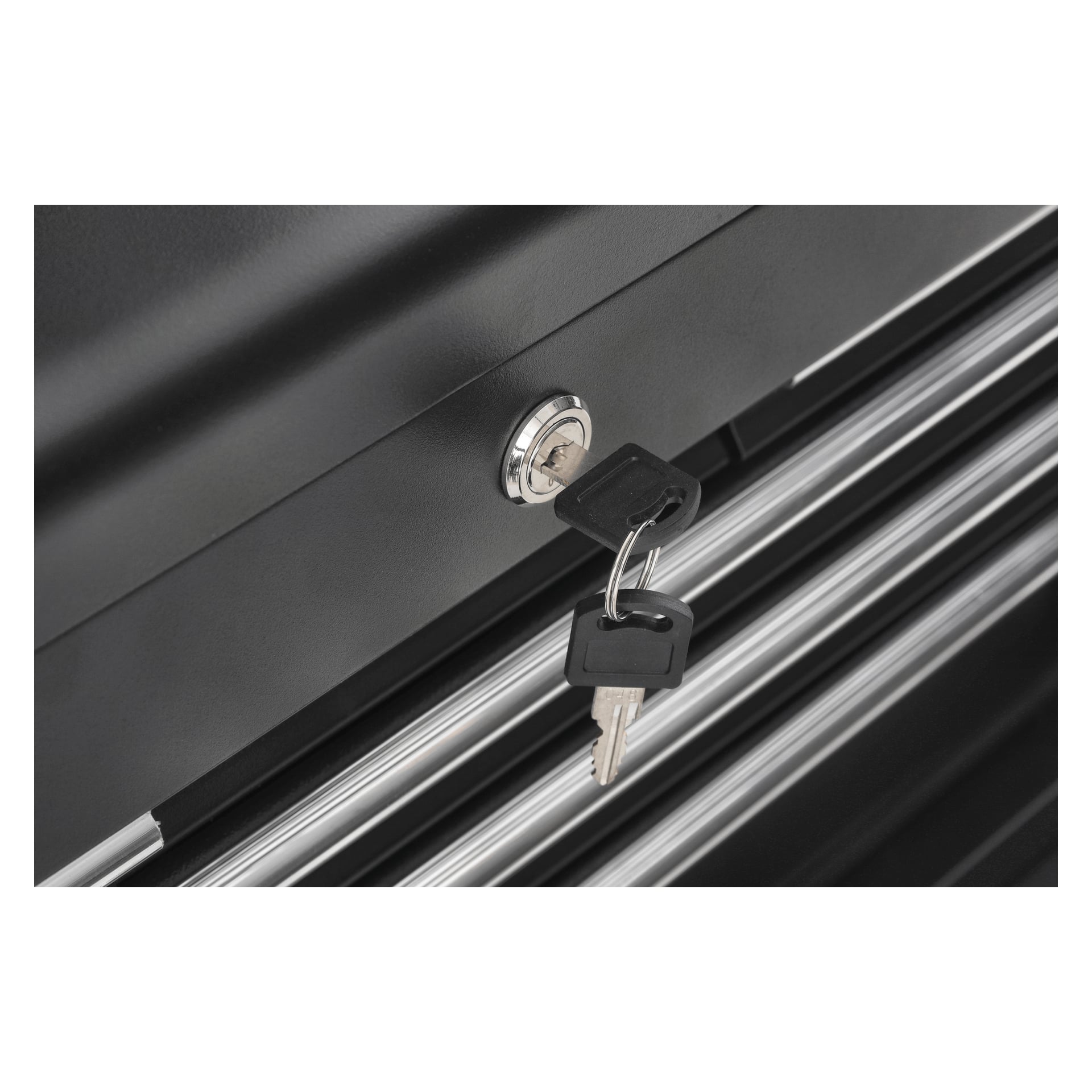 En detaljerad vy visar två nycklar hängande från en liten nyckelring, insatta i låset på en Hard Head Tool-vagn med svarta metalllådor eller skåp med silverfärgade horisontella handtag.