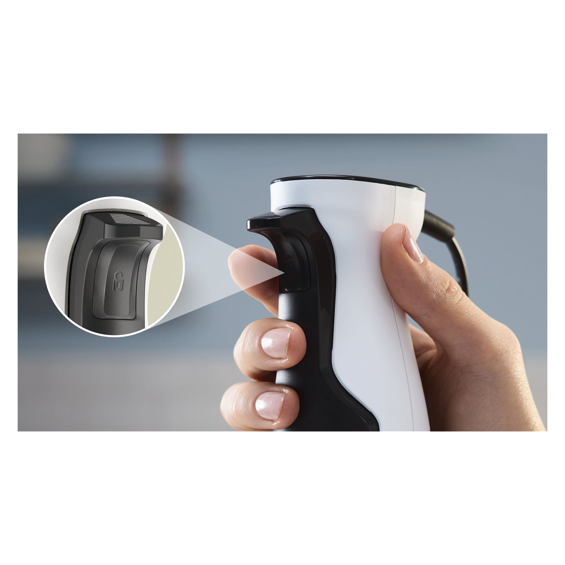 Eine Hand hält den Bosch Home Hand Mixer ErgoMaster MSM4W220, weiß mit schwarzen Akzenten, und konzentriert sich auf eine Nahaufnahme des schwarzen Knopfs mit einem Schlosssymbol, das das Sicherheitsschloss betont. Der Hintergrund ist verschwommen.