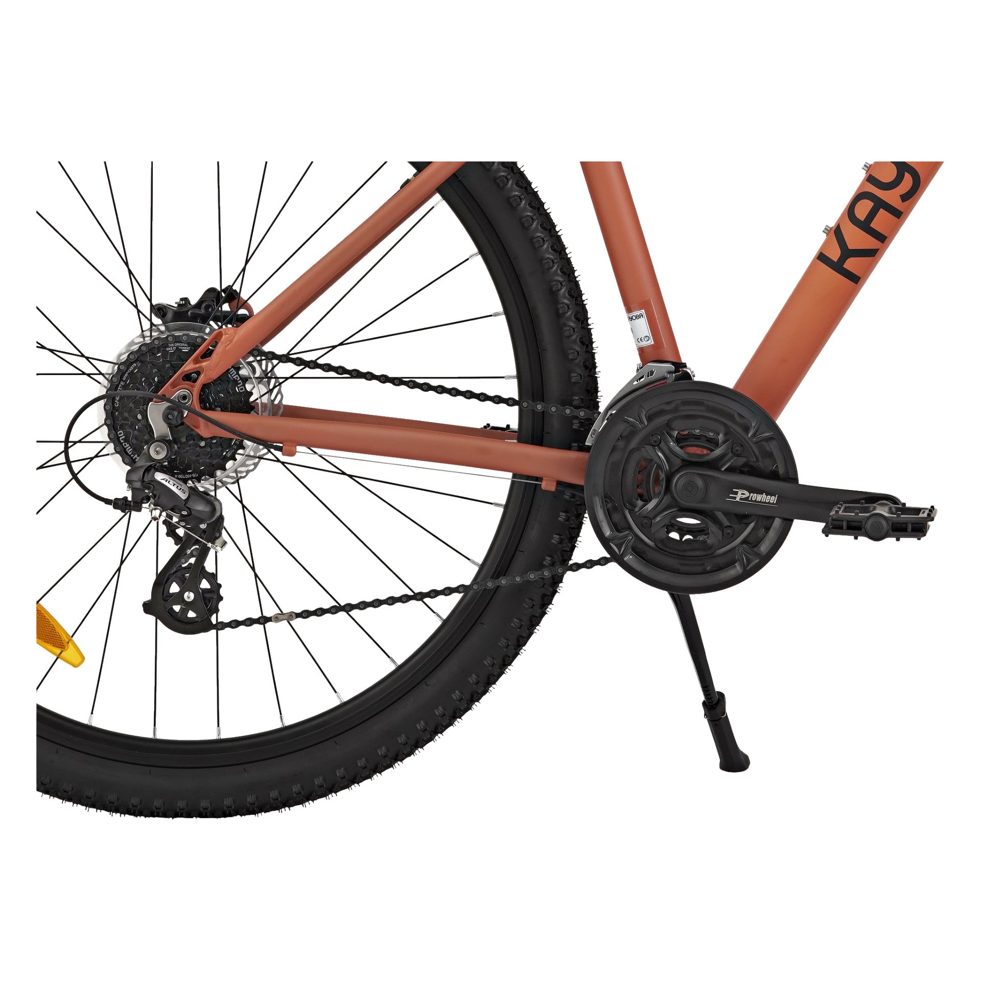 Detaljerad vy av bakdelen på en Kayoba Mountain bike Freedom 3, med framhävning av bakhjulet, växlar, kedja, pedal, vevaxel, stöddel och en del av ramen. Däcket är utrustat med ett knoppigt mönster.