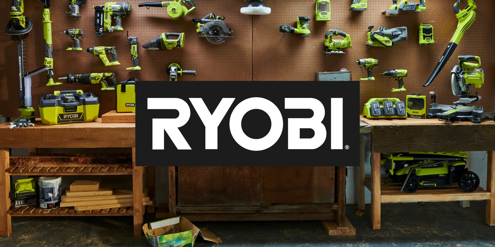 Gröna Ryobi elverktyg, batterier och laddare är organiserade på en pegboard och en arbetsbänk med Ryobi-logotypen i mitten.