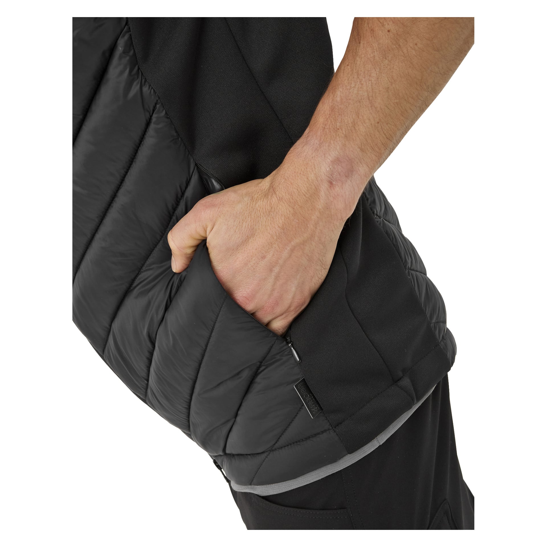 En persons högra hand är i sidofickan på en svart, vadderad herrvästervik från Kayoba Outdoor. Endast armen, handen och en del av dräkten syns, vilket framhäver jackans textur.