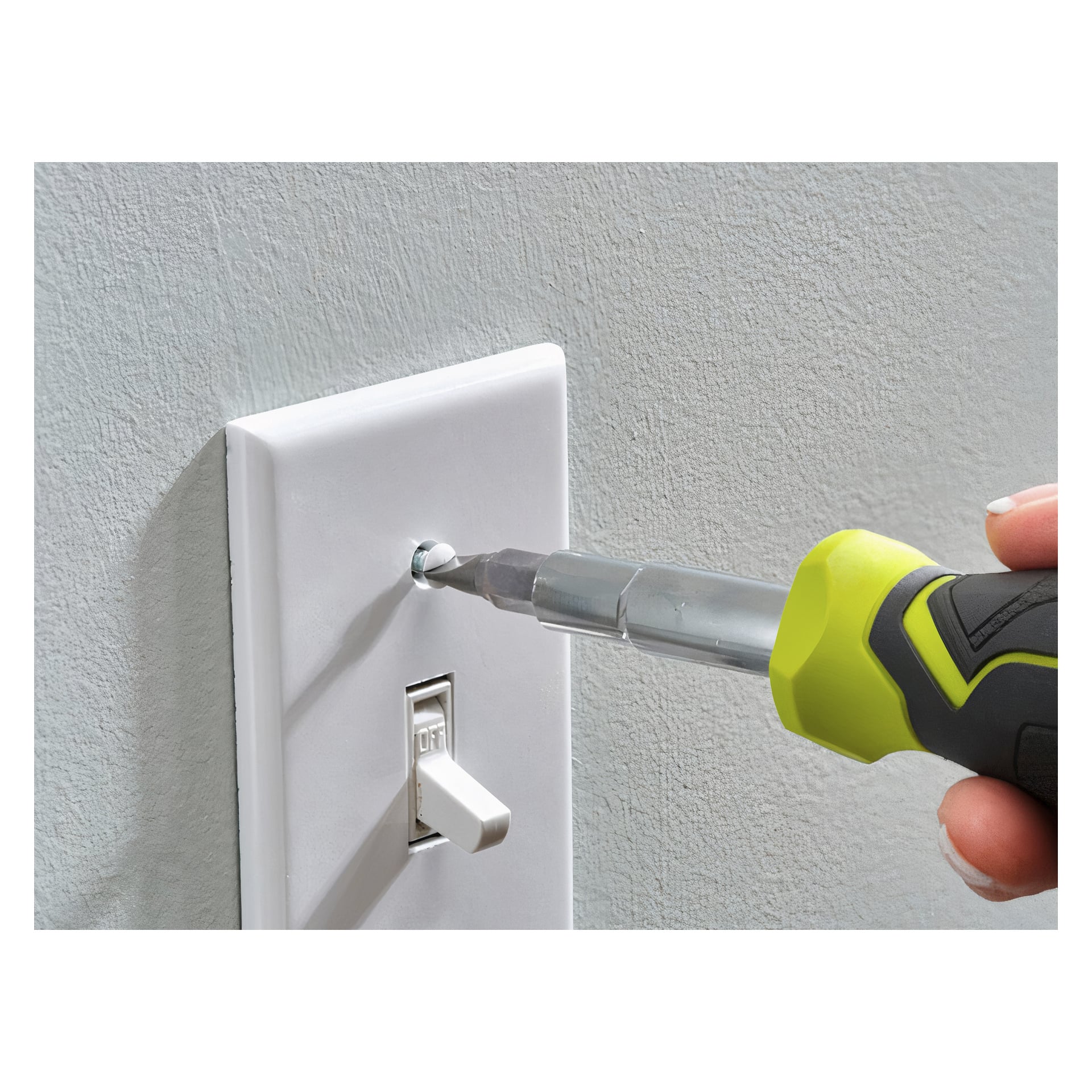 En hand manövrerar en Ryobi Bit-skruvmejsel från 11-i-1 RHSDM1101 7-delars set, som har ett grönt och svart handtag, för att fästa en skruv på ett vitt strömbrytarlock fäst vid en ljusgrå vägg. Strömbrytaren är avstängd.