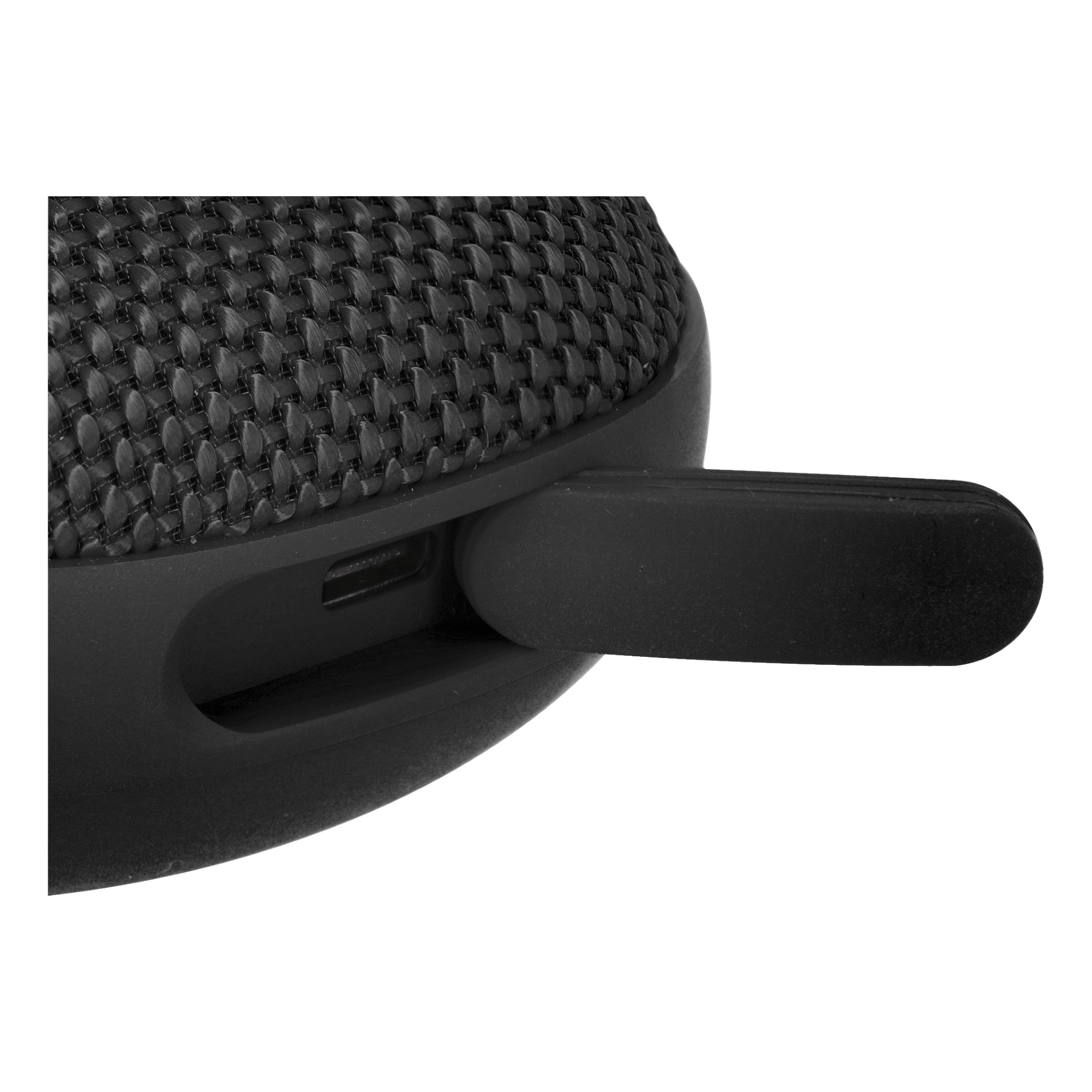 En svart Bluetooth-högtalare med en vävd textur visas i närbild, där ett USB-minne är inkopplat i en av sidoportarna. En annan liten laddnings- eller dataport är delvis synlig i närheten.