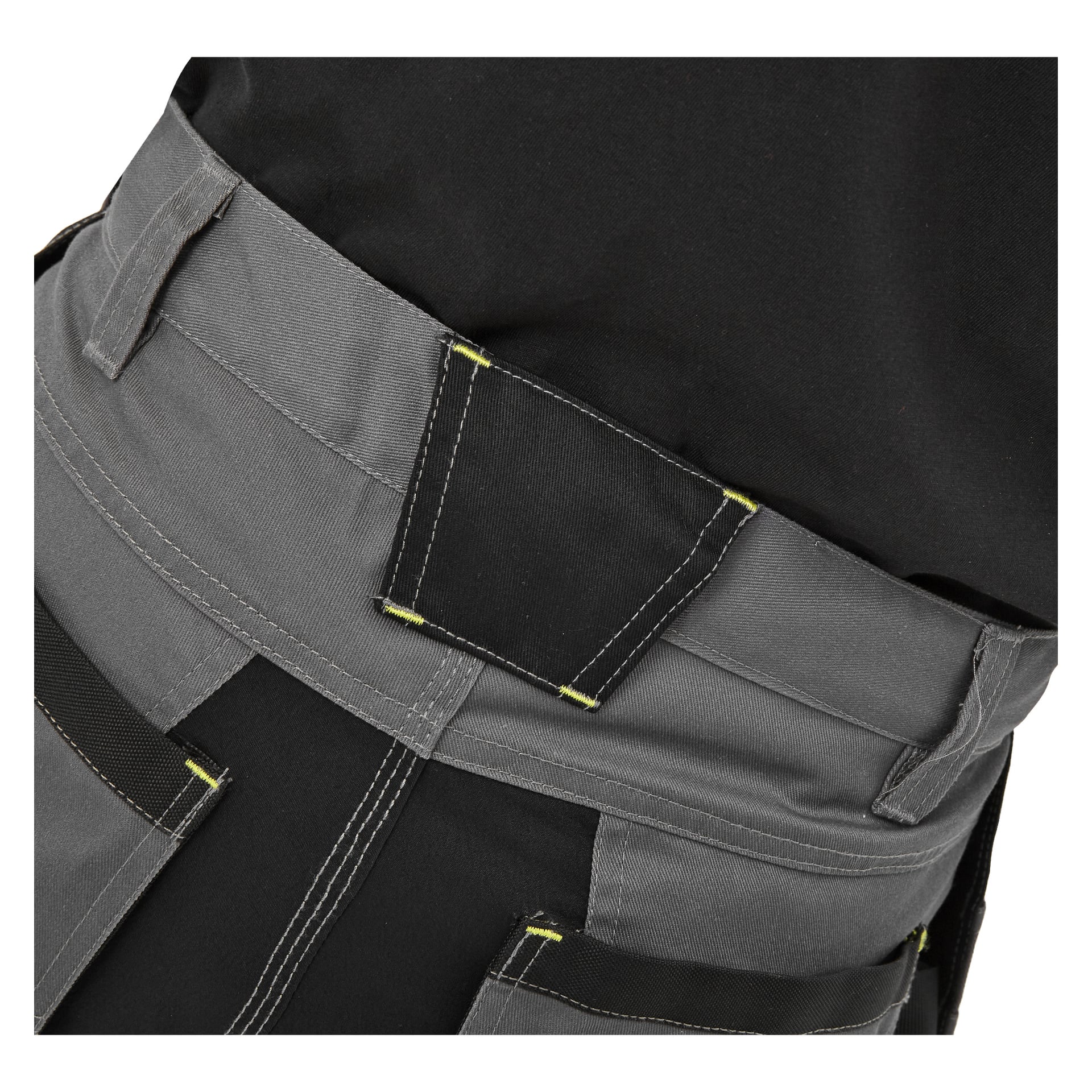 Detaljerad närbild av midjebandet och överdelen på Bluewear Men's Rex arbetsshorts, med grått och svart tyg och kontrasterande gula sömmar. Bilden betonar fickdesignen och stygnmönstret, som visas på en person klädd i svart skjorta.