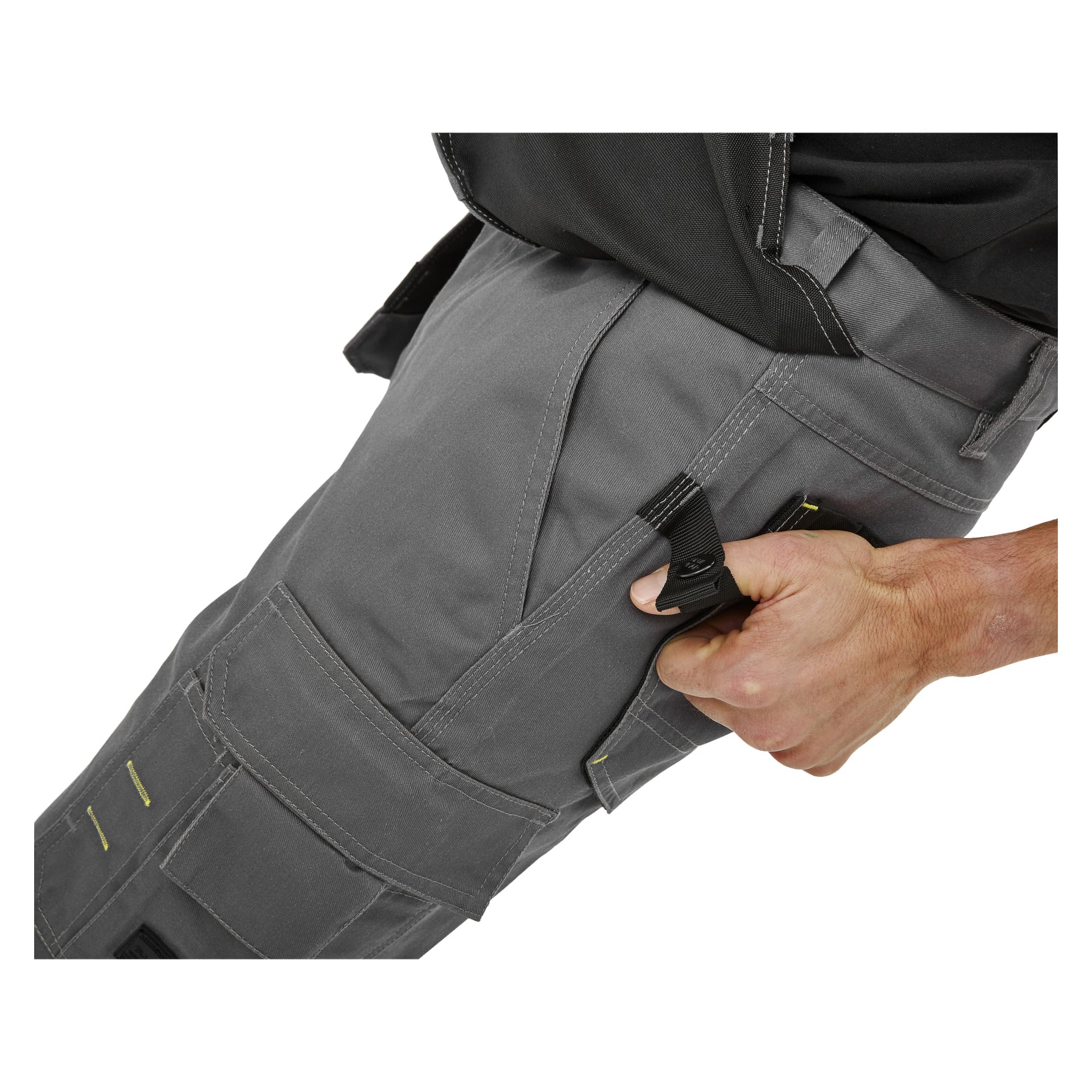 En hand drar i en svart tygögla på sidan av grå Bluewear Men's Workshorts Rex, med flera fickor och gula stygndetaljer.