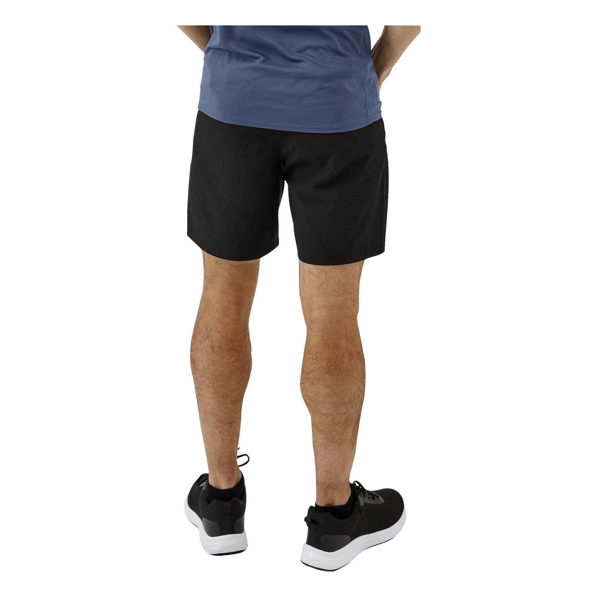 En person syns bakifrån, klädd i en blå skjorta och Kayoba herrträningsshorts, tillsammans med svarta träningsskor med vita sulor. Endast utsikten från midjan och nedåt är synlig.