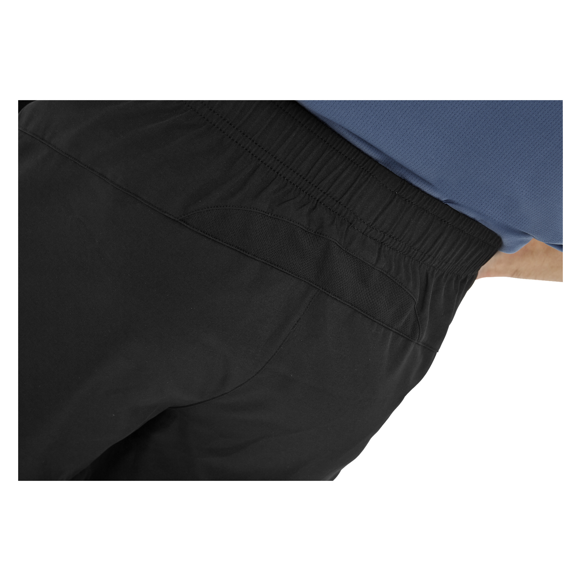 Närbild på en person klädd i svarta Kayoba herrträningsshorts med resår i midjan och en blå skjorta, som betonar midjebandet och höftområdet.