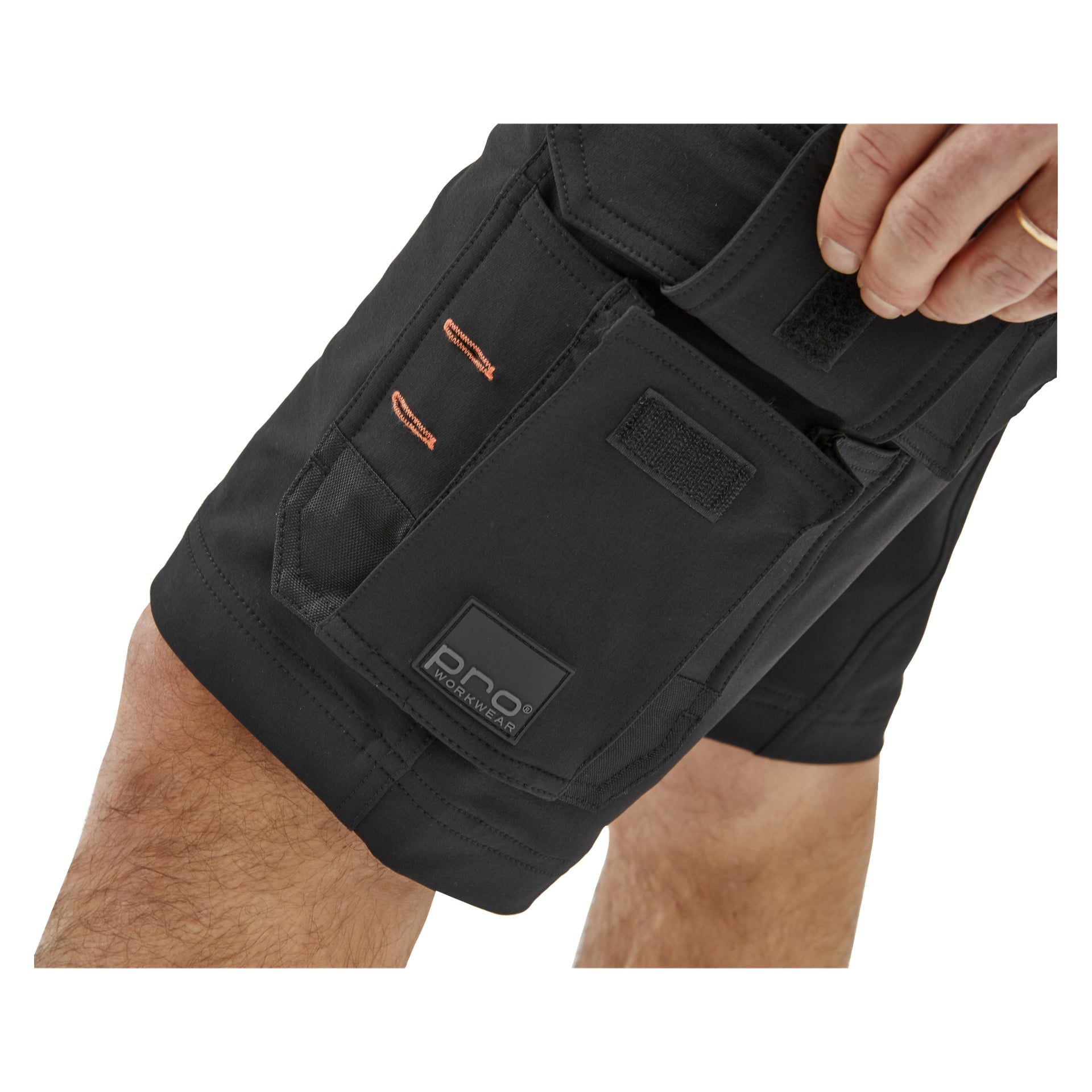 En närbild på någon i Steve herrshorts från Bluewear Pro Workwear, med fokus på en ficka med Bluewear Pro Workwear-etiketten och en flik, medan personen greppar fickstängningen.
