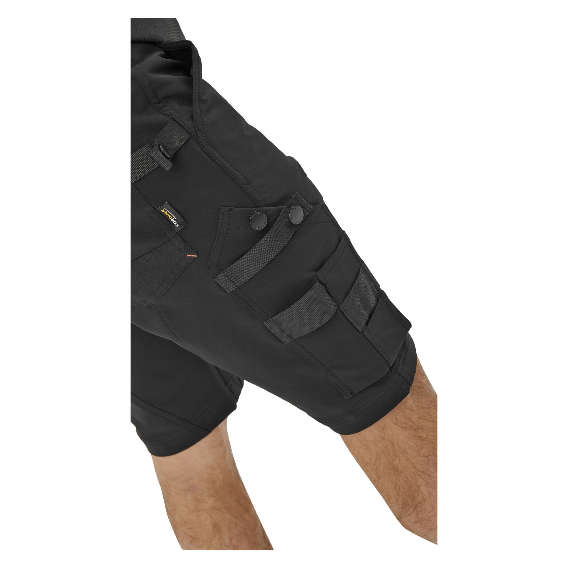 Detaljerad vy av en person klädd i svarta Bluewear Pro Workwear Men's Steve work shorts, som visar flera fickor, remmar, tryckknappar och framträdande sömmar. Låret och en del av knät är synliga, vilket betonar det tåliga och praktiska materialet.