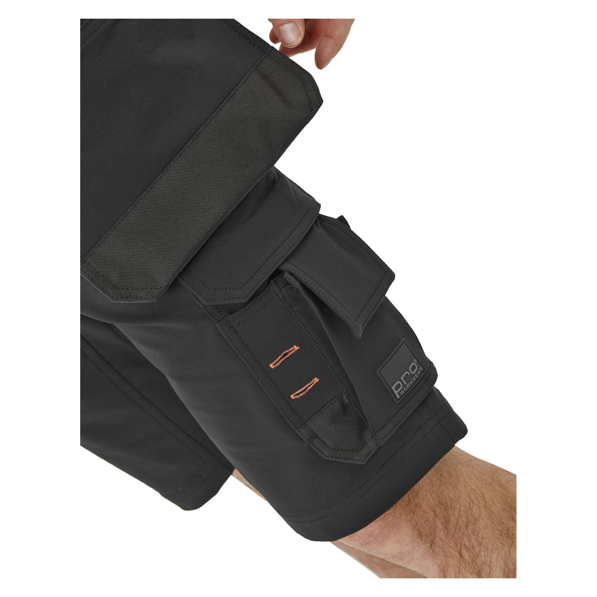 En närbild på någon som bär svarta Bluewear Pro Workwear Steve herrshorts, som har flera fickor och en synlig Pro-logotyppatch på en av de nedre fickorna. Personens hand vilar nära den övre fickan.