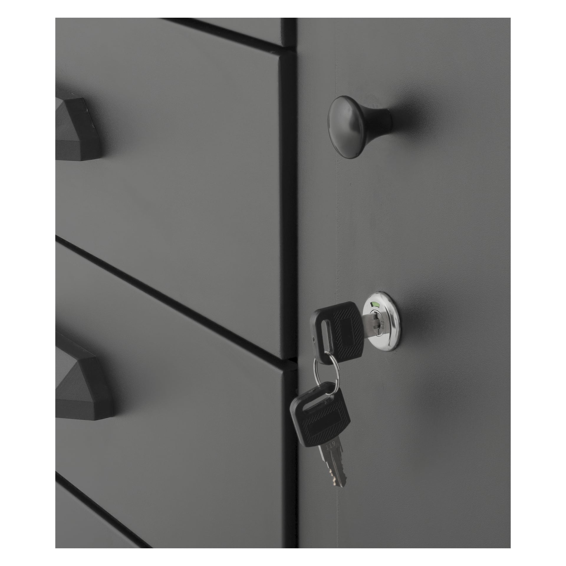 Detaljerad vy av den svarta Hard Head Workbench med integrerat förvaringsutrymme, som visar en låsbar låda. Två nycklar är insatta i låset, och lådhandtagen är tydligt synliga. Skåpet har en slank, matt yta.