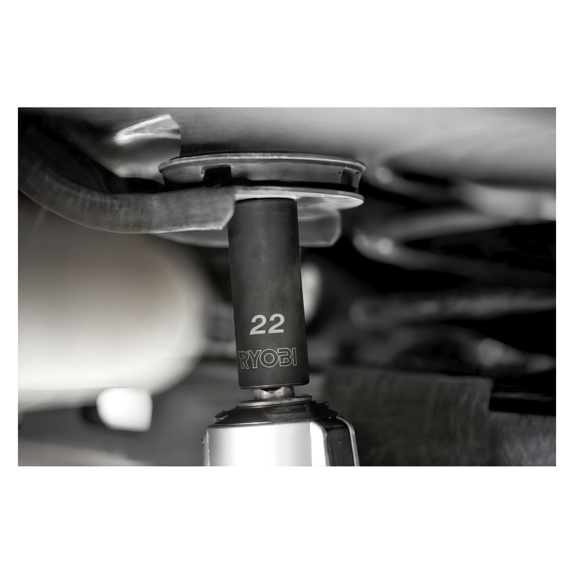 En detaljerad vy av en Ryobi RHDIS10PC 10-delad hylsa visar en 22 mm hylsa fäst, som aktivt används på en bildel. Fokus ligger på hylsan och verktyget, med olika mekaniska komponenter synliga i omgivningen.