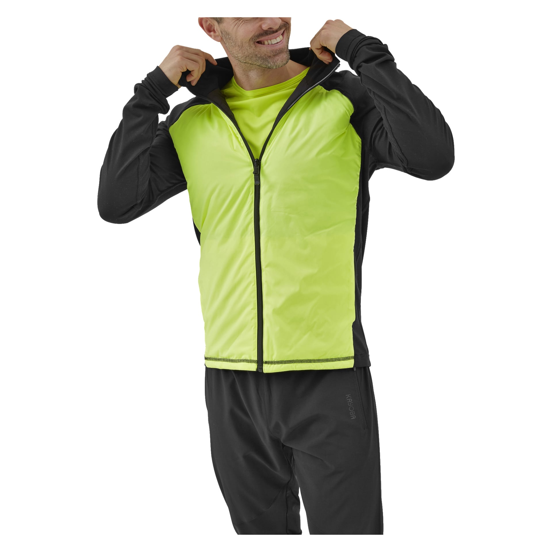 En man modellerar Kayoba Reversible Running Jacket for Men Innsbruck, som har en livfull gul dragkedja framtill och kontrasterande svarta ärmar. Han ler när han justerar jackkragen och tar på sig svarta byxor.