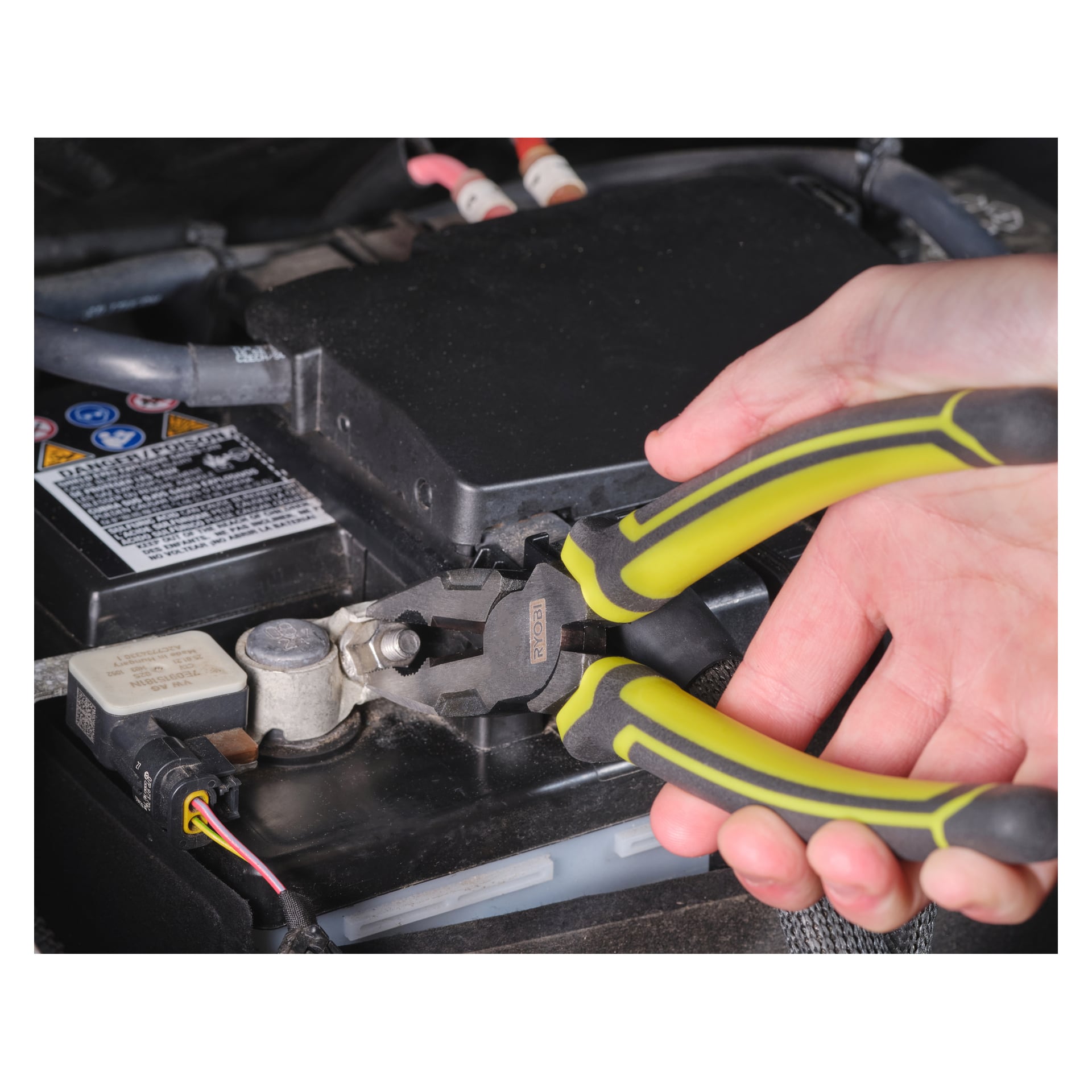 En hand använder Ryobi Combination Pliers RHCP180 för att greppa en terminalklämma på ett bilbatteri, med synliga kablar och en varningsetikett på batteriet.
