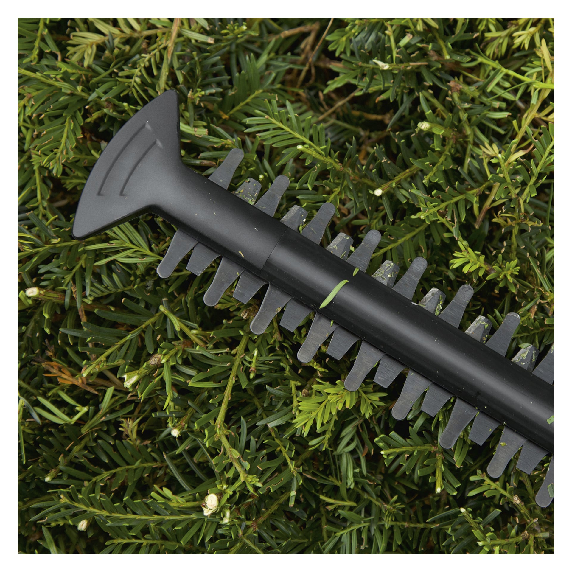 En detaljerad vy av Bosch Power 4 All EasyHedgeCut 18-45 häcksaxbladet som ligger på frodiga gröna häckblad. Det svarta, tandade bladet är framträdande, med en del av handtaget på vänster sida.