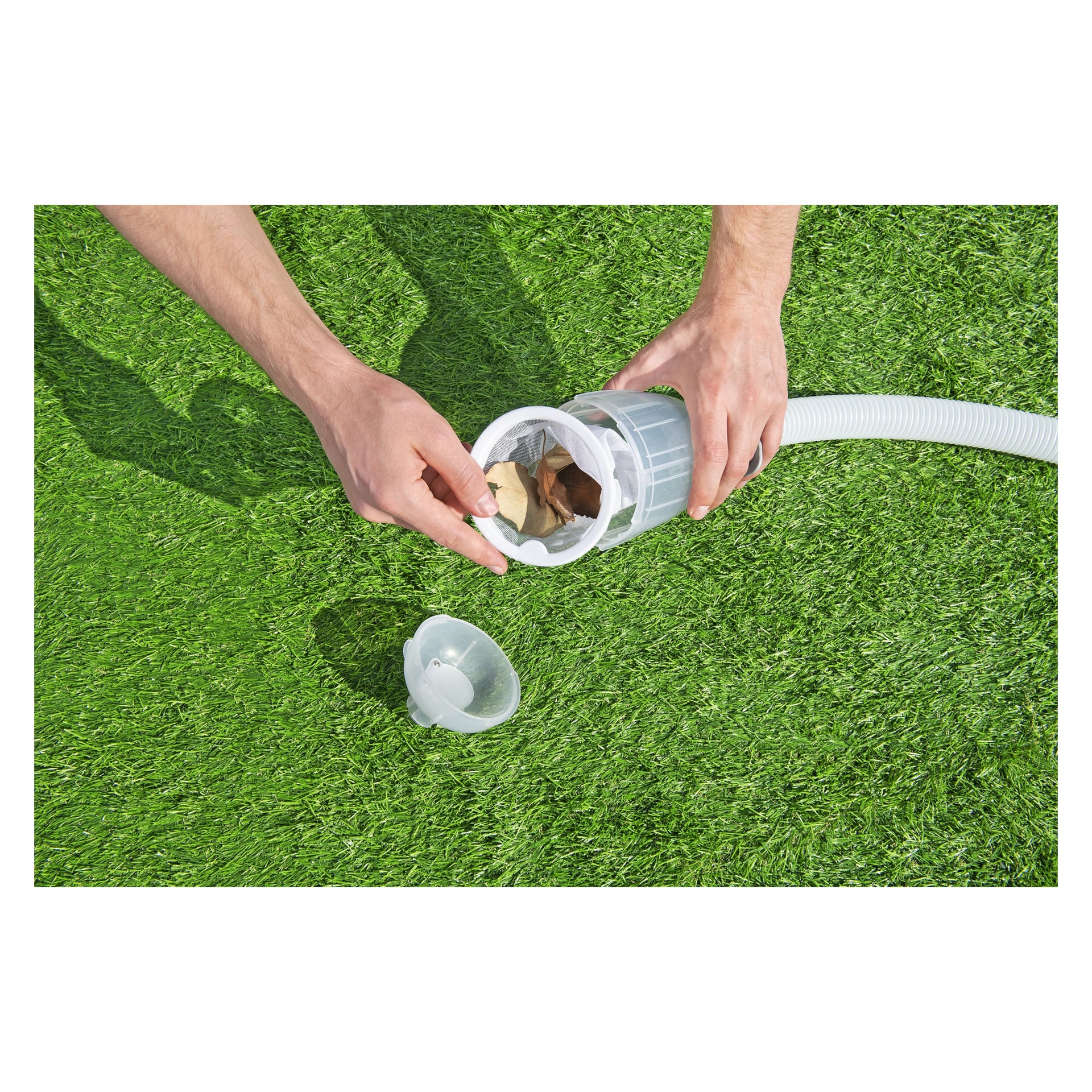 Någon rengör en poolfilterkorg med Bestway AquaClean 3-delad rengöringssats, tar bort löv och skräp, medan filterlocket står nära på konstgräsmattan.