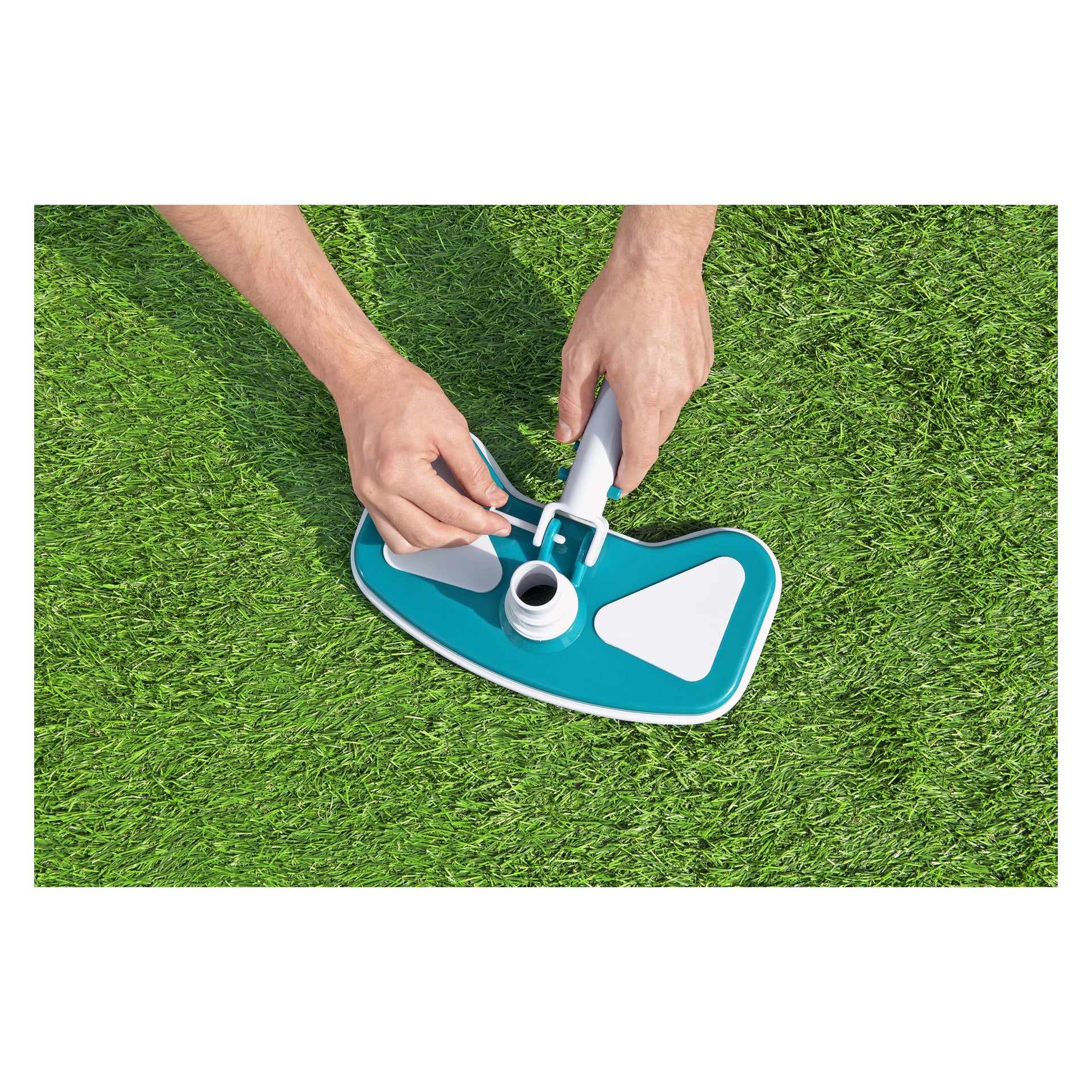 Man kopplar en stång till det blåvita dammsugarhuvudet med en central vit koppling från Bestway AquaClean 3-delade poolrengöringsset, och monterar den på grönt konstgräs.