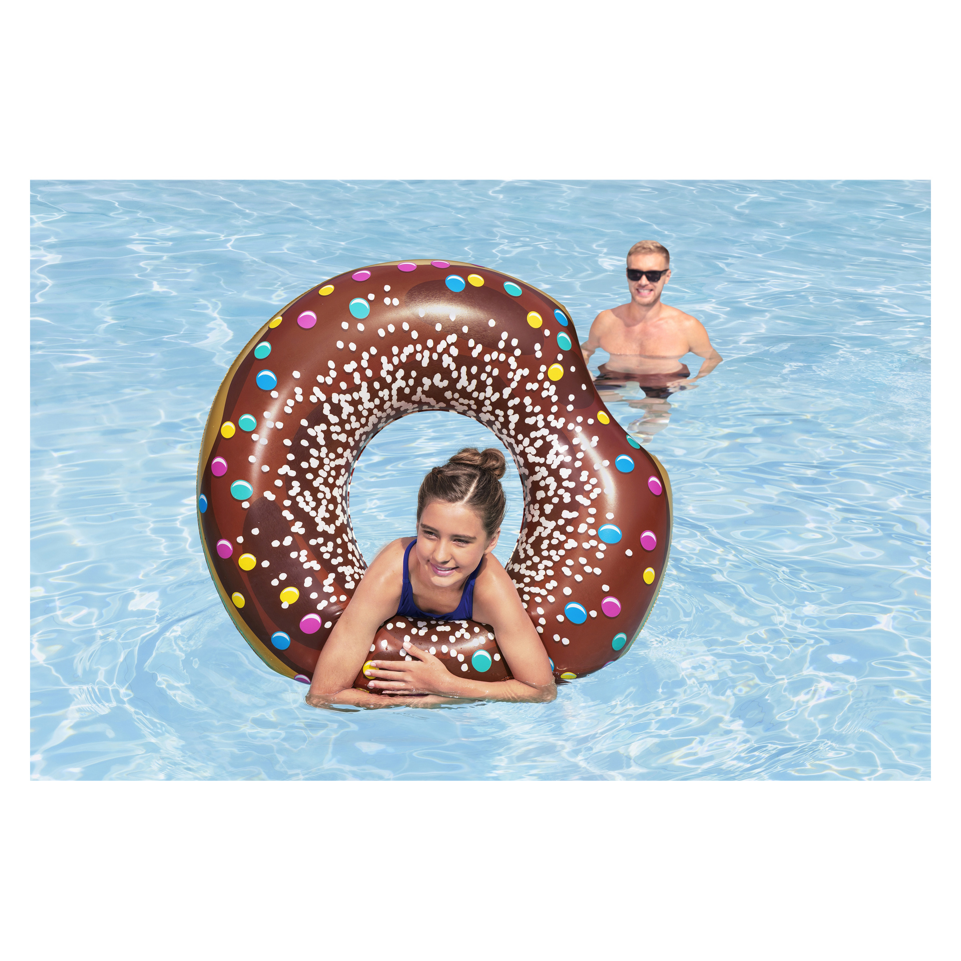 En kvinna i blå baddräkt ligger på en stor, chokladmunkformad Bestway Swim-ring medan en man med solglasögon står bakom henne i poolen.