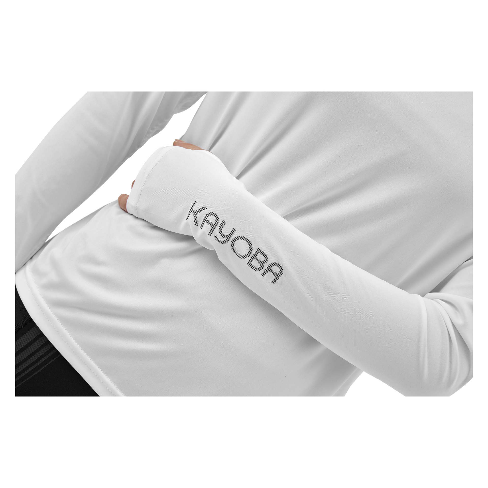 Någon bär Kayoba Atlanta women's functional top, en långärmad vit skjorta med "KAYOBA" tryckt i grått på ena ärmen. Endast bålen och armen visas, med vänster arm böjd och handen vilande på höger sida.