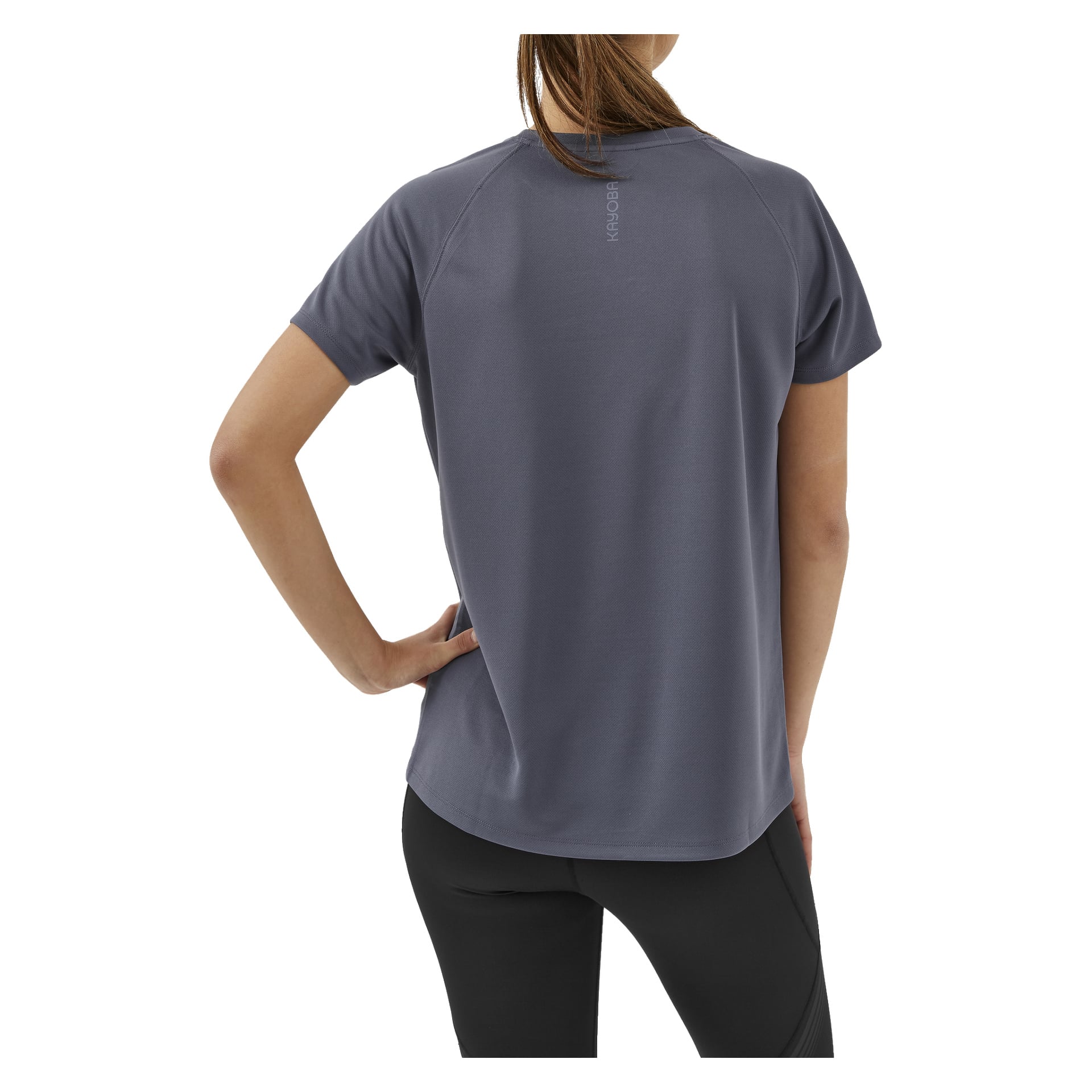 En person poserar med ena handen på höften och visar ryggen på Kayoba Women's Functional Top Tokyo – en avslappnad, kortärmad grå skjorta – som bärs med svarta byxor.