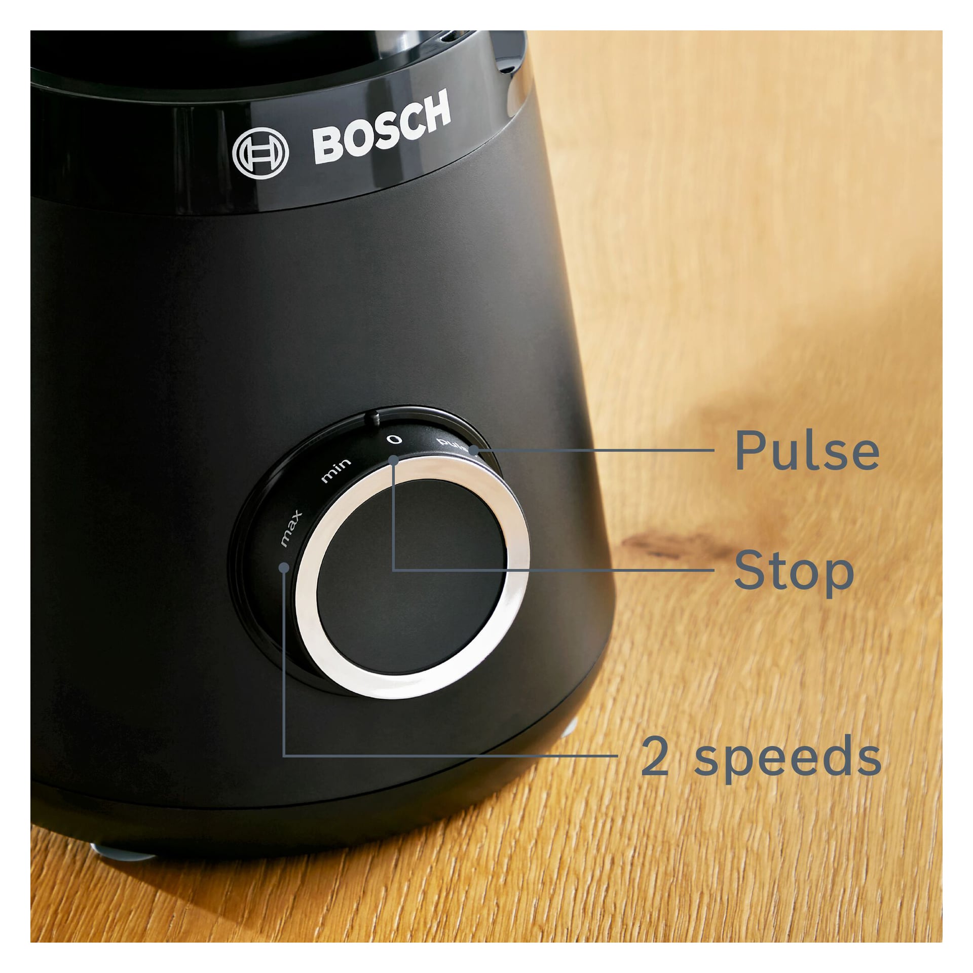 Närbild av en Bosch Home Blender MMB6141B kontrollratt med märkta inställningar: Pulse, Stop och två hastighetsalternativ. Ratten är för närvarande inställd på Stopp. Den svarta mixern står på en träyta.