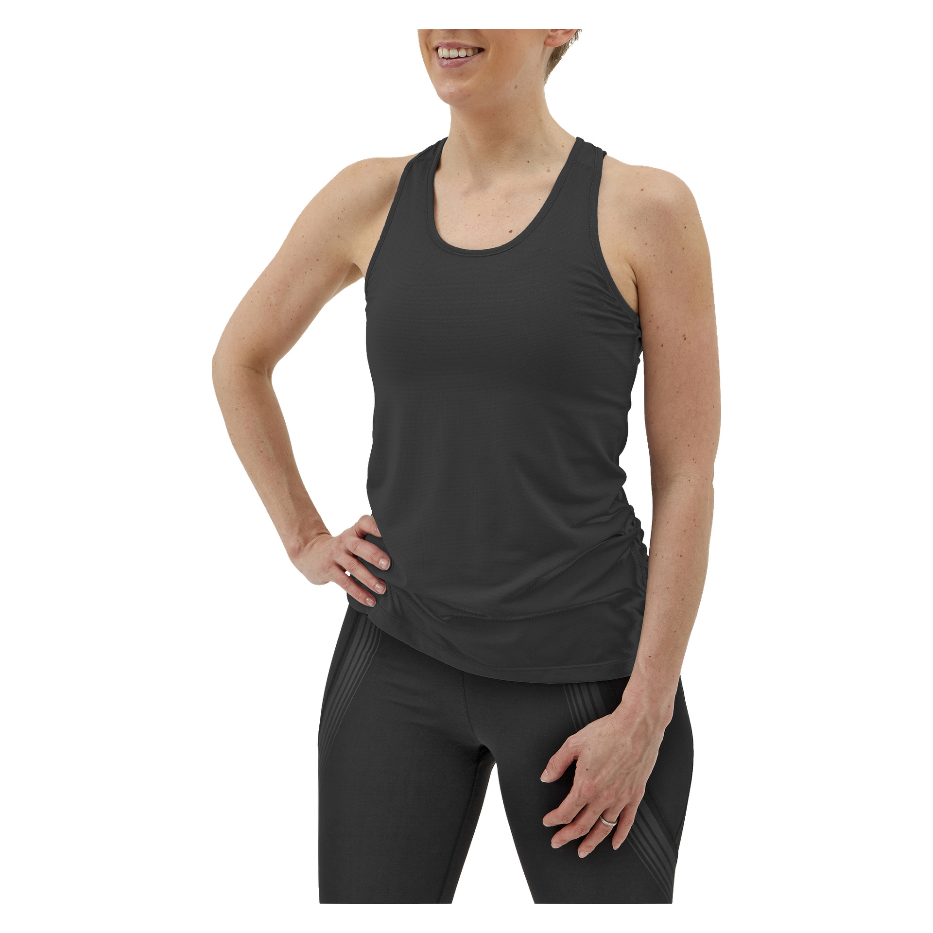 En kvinna bär Kayoba Women's Training Top Albany tillsammans med svarta leggings, ler självsäkert med ena handen på höften och den andra vilande på låret.