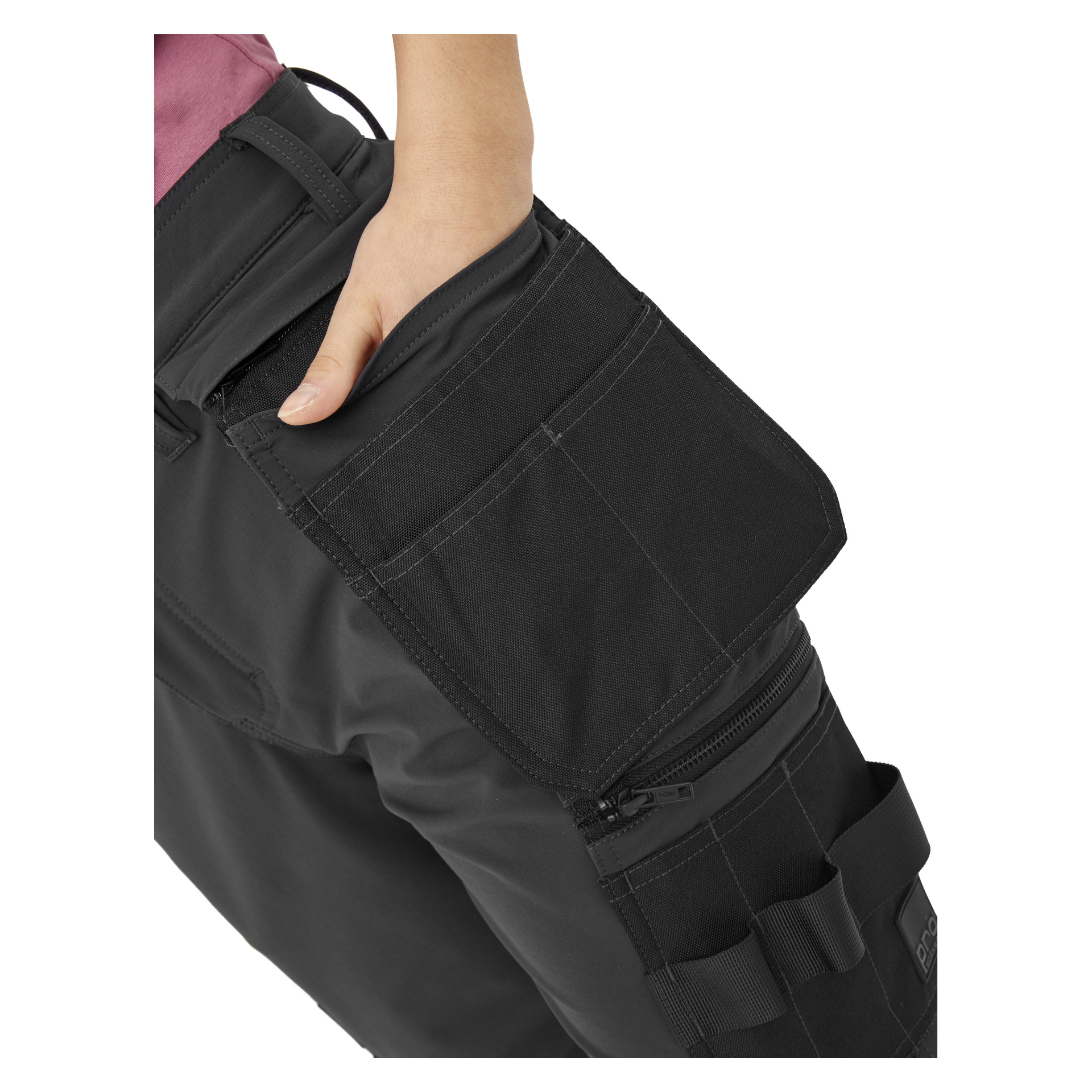 En person kledd i Bluewear Pro Workwear Stella dameshorts med svarte cargolommer, en klaff åpen og hånden delvis inne i lommen. Shortsene har flere rom og fremtredende sømdetaljer. De har også på seg en rosa skjorte.