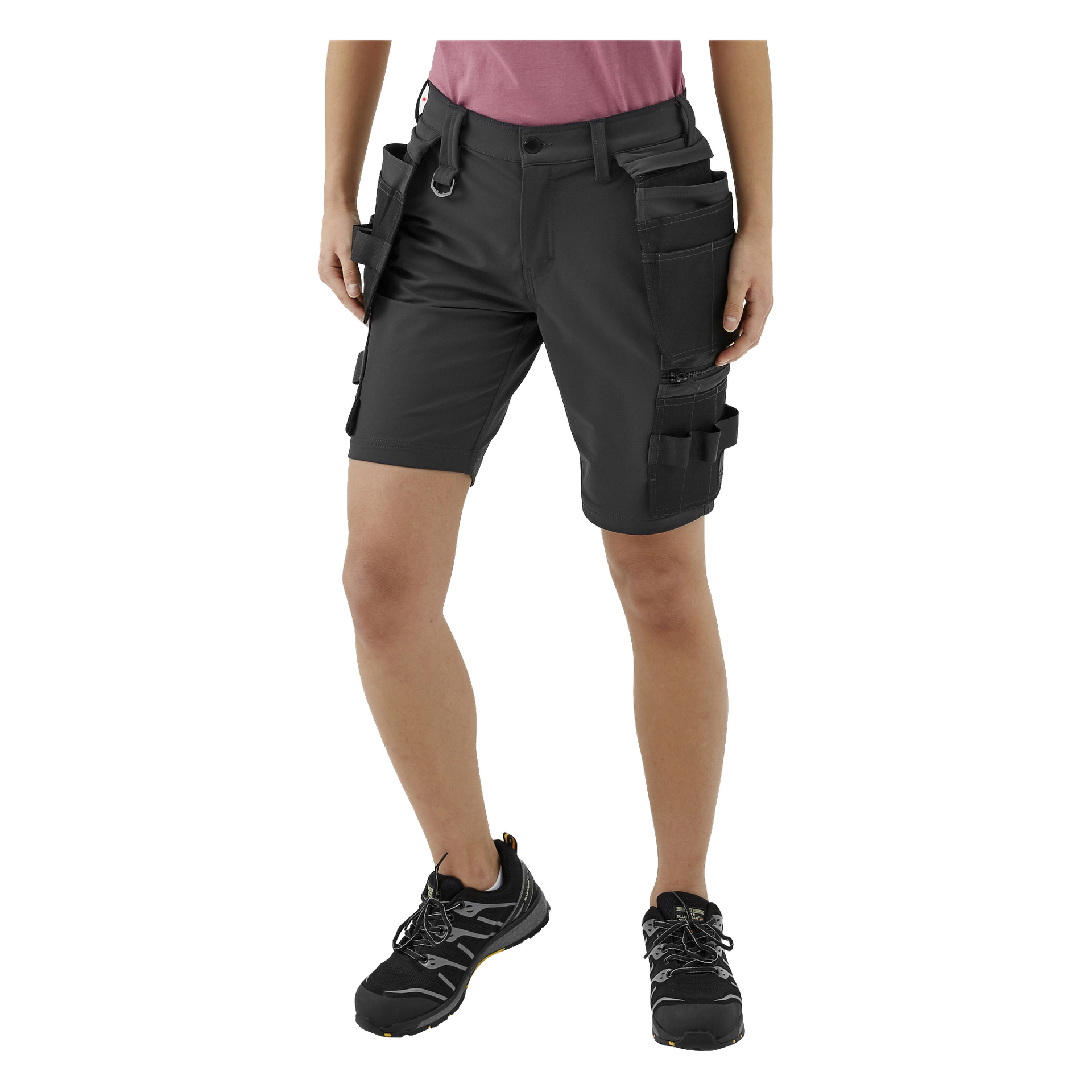 Eine Person steht mit dem Gesicht nach vorne, trägt die Stella-Arbeitsshorts von Bluewear Pro Workwear – schwarze Utility-Shorts mit mehreren Taschen und Schlaufen – dazu ein rosa Hemd und schwarze Sportschuhe.