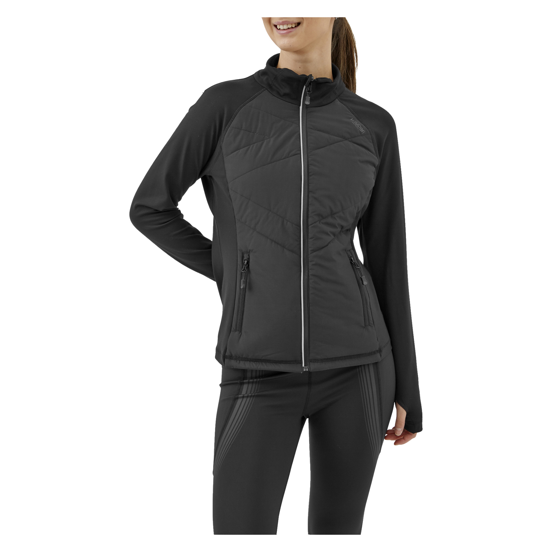 Eine Person, gekleidet in die Kayoba Women's Reversible Running Jacket Innsbruck und schwarze Leggings, steht mit einer Hand auf der Hüfte ruhend. Die schwarze Jacke mit hohem Kragen hat zwei Taschen mit Reißverschluss. Die Person lächelt und dreht sich etwas zur Seite.
