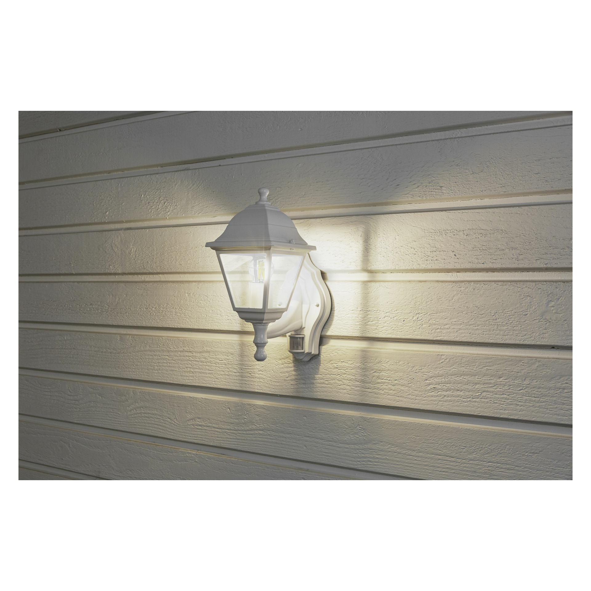 Eine EKVIP Wandlampe mit Bewegungsmelder und klarem Glas ist an beige horizontaler Verkleidung befestigt und beleuchtet die strukturierte Wand mit Licht- und Schattenmustern.