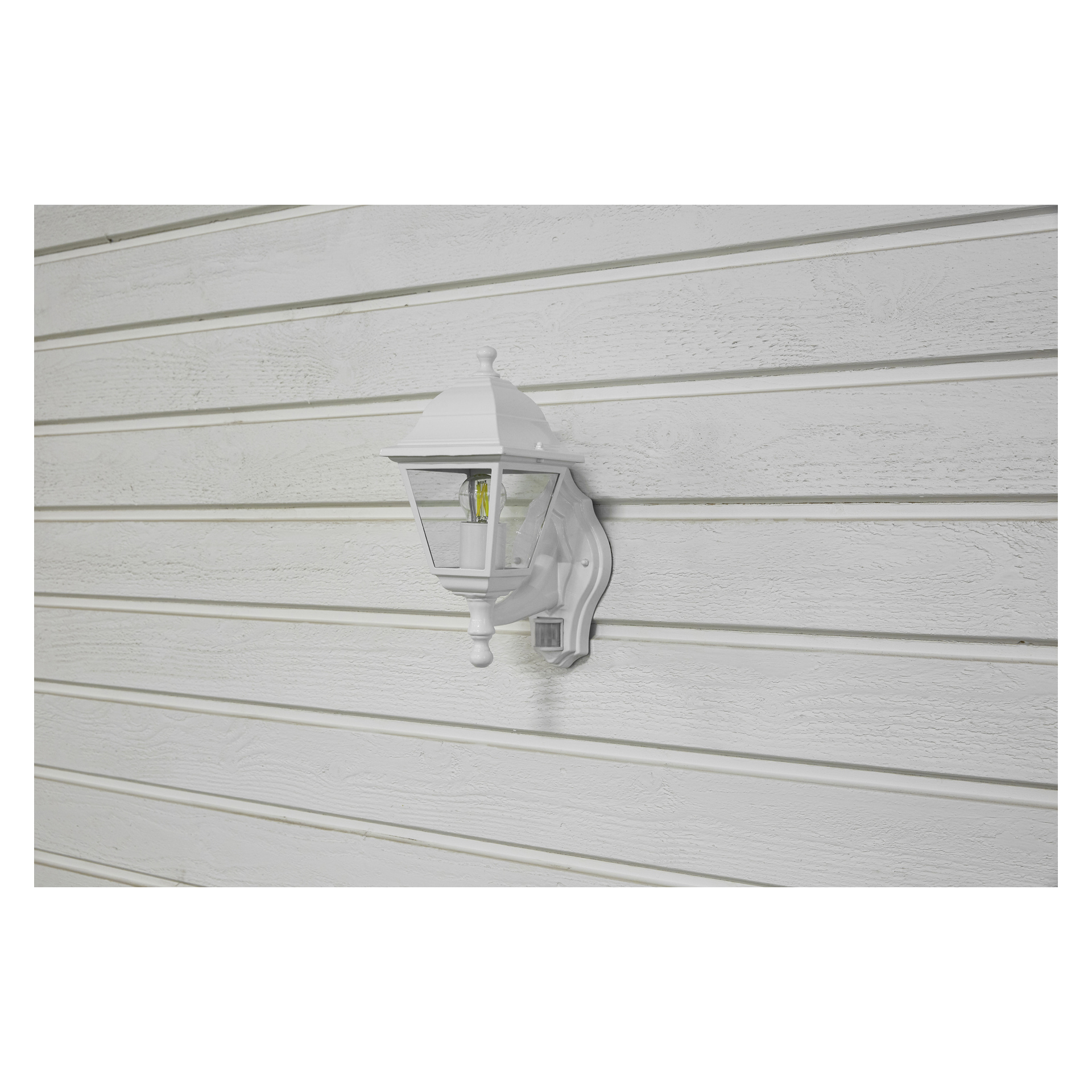 Eine weiße EKVAP-Wandlampe mit Bewegungsmelder ist auf einer weißen Holzwand mit horizontalen Dielen und markanter Holzmasur installiert. Die Lampe bleibt unbeleuchtet.